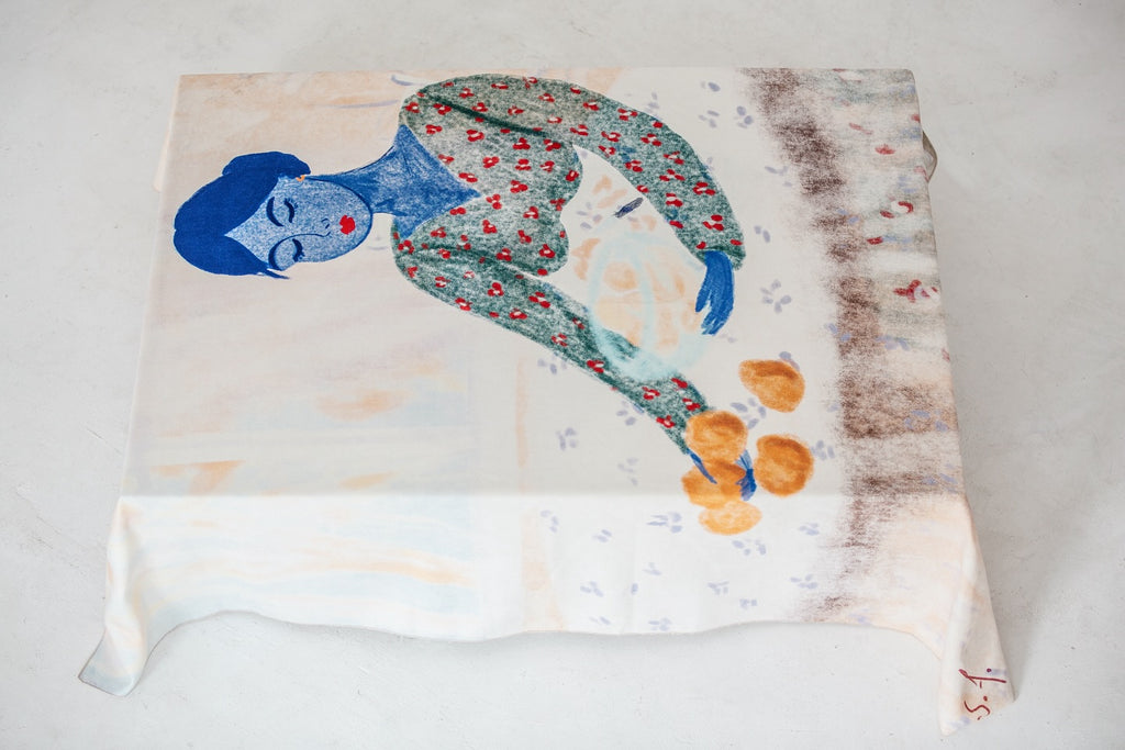 Fabric with a printed design of a stylized figure on a white background. Tablecloth by DAE