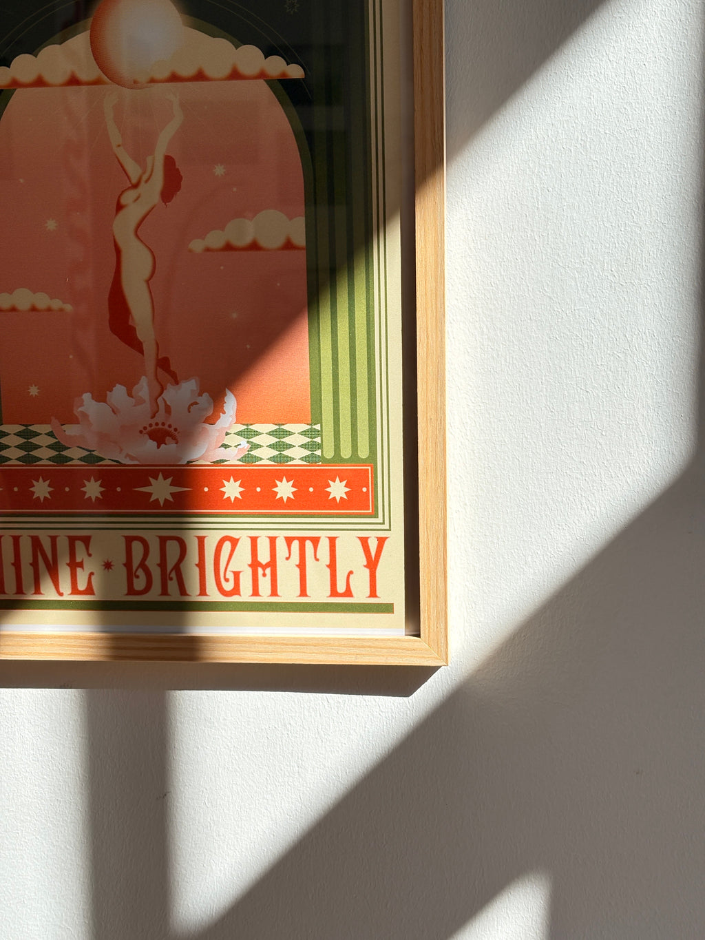 “Shine Brightly” poster displayed on a sunlit wall, highlighting its radiant colors and elegant wooden frame
