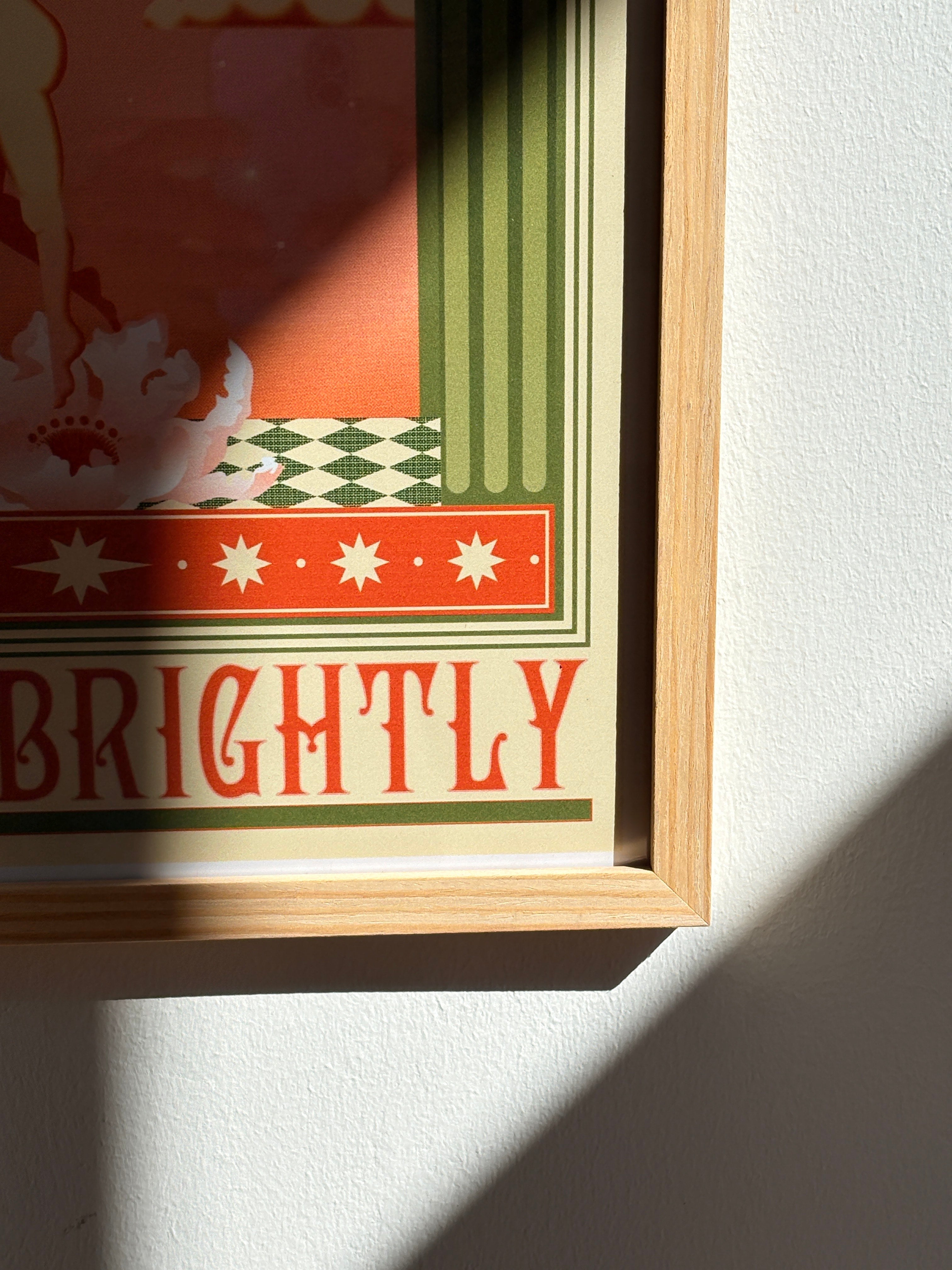 Close-up of “Shine Brightly” poster showing retro typography and vibrant sunlight reflection on the frame