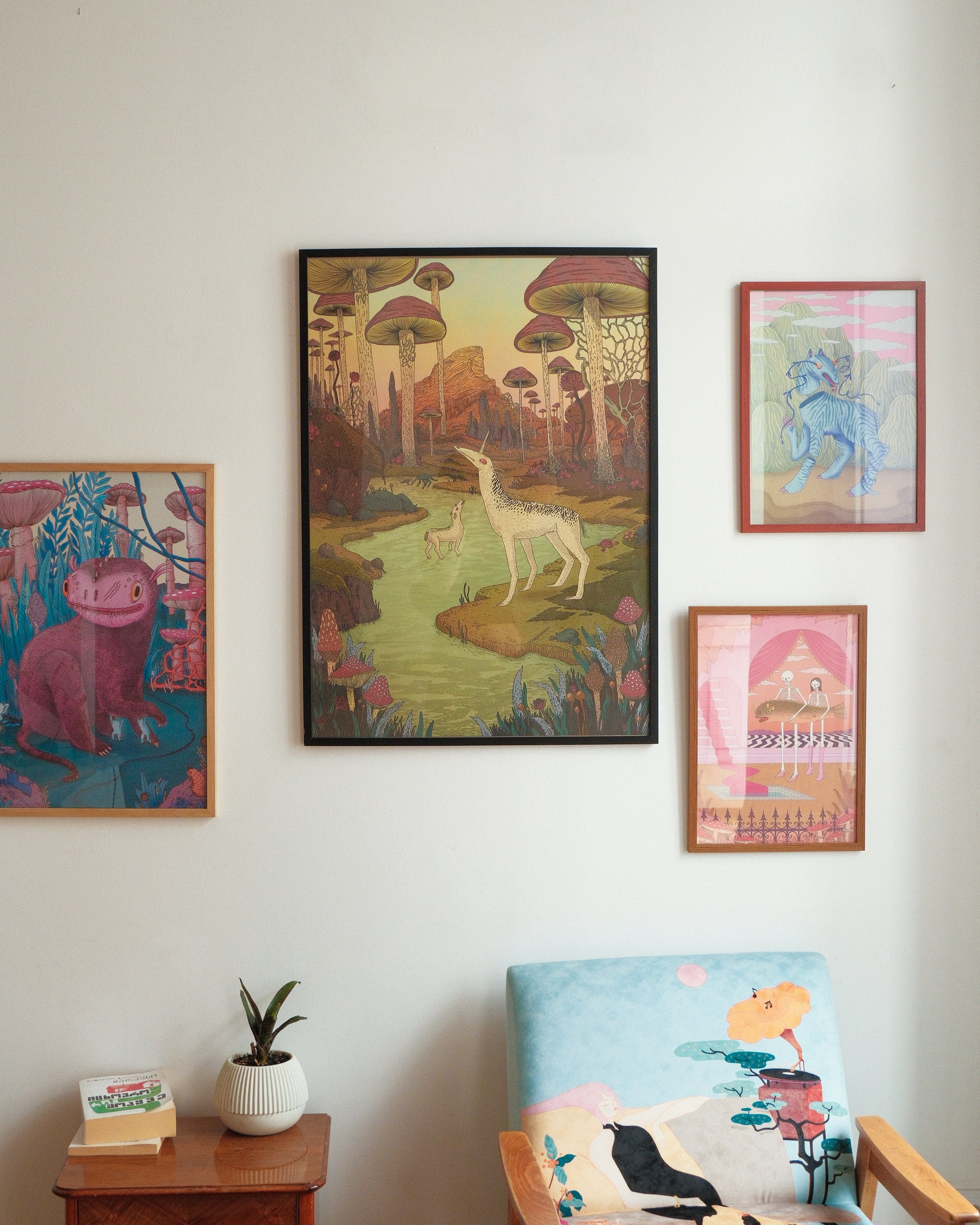 Colorful wall art prints on a white wall with a small table and chair in the foreground.