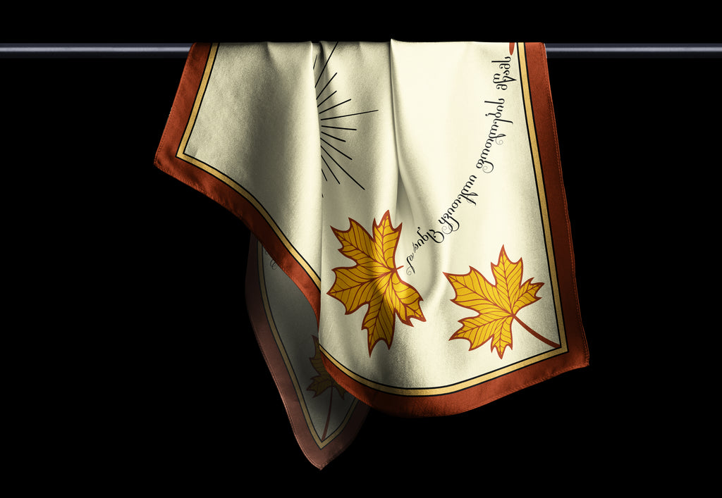 A scarf with a white background featuring a brown maple leaf design and a red and white striped border.