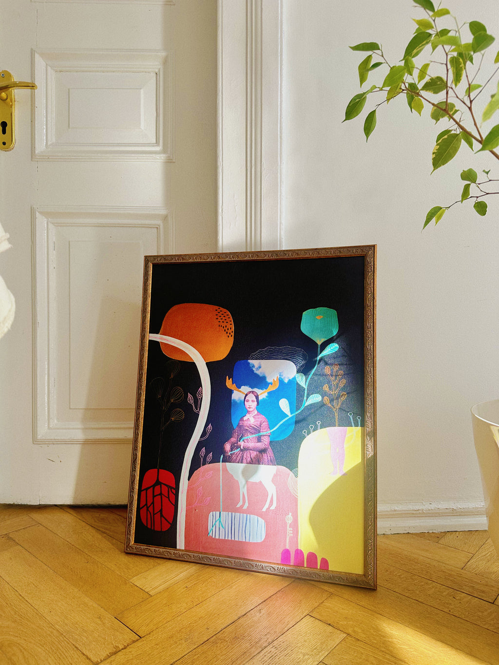 Poster “In Book Cover Style” by Margarita Brum framed and placed on wooden floor near a plant