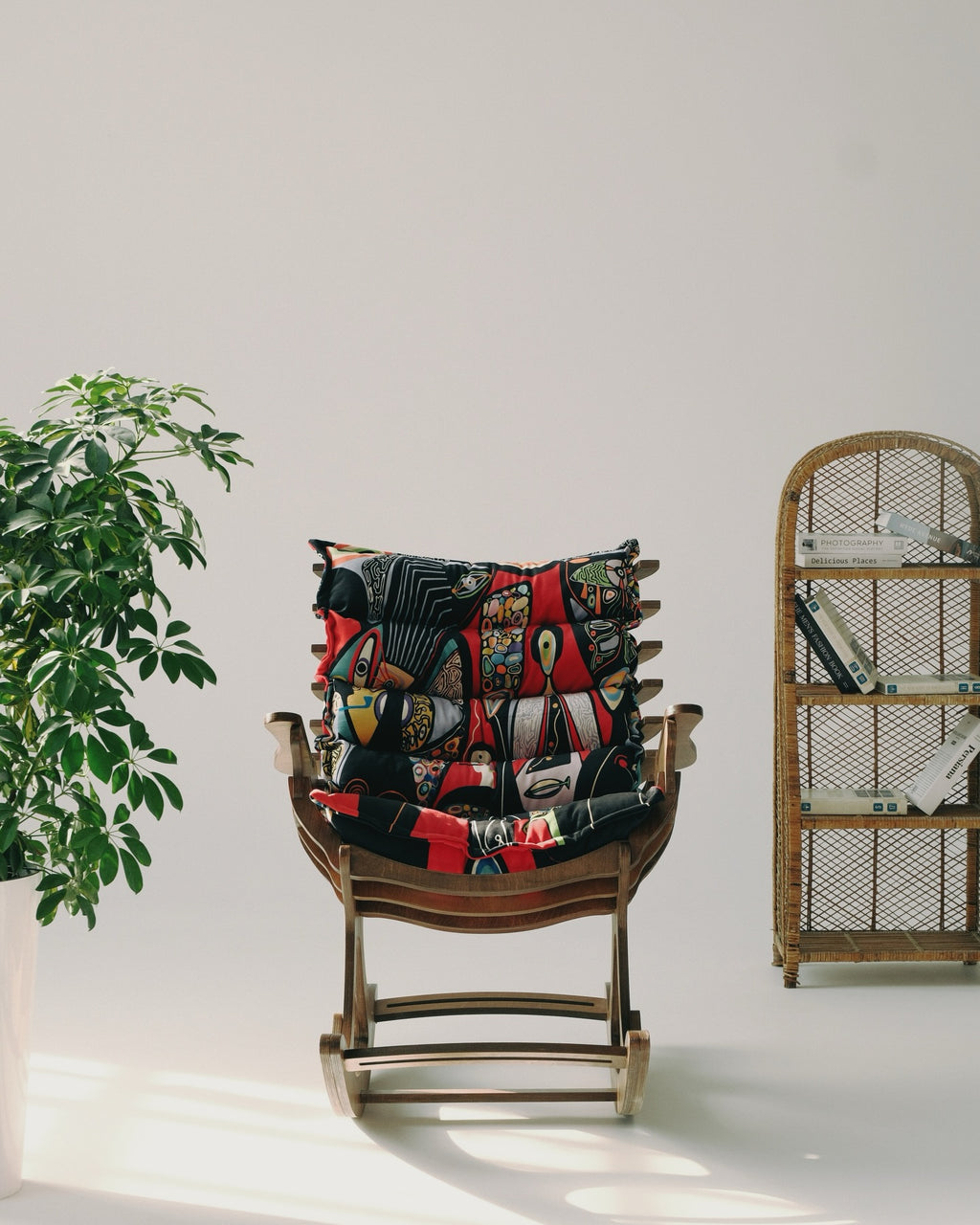 Decorative pillow on a wooden chair with a plant and bookshelf in the background