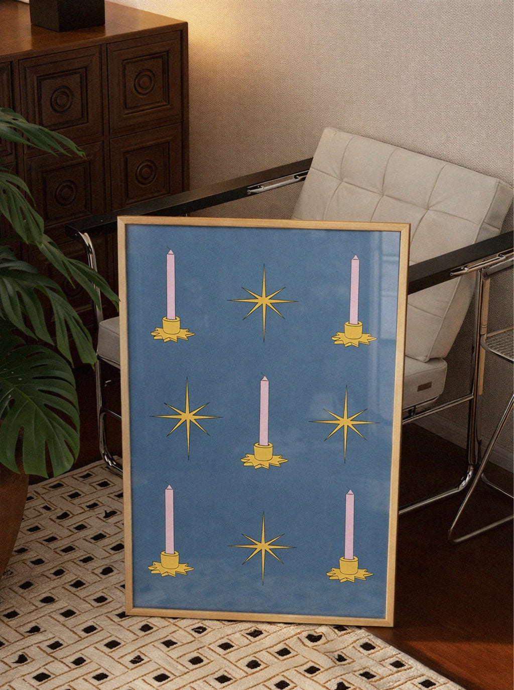 Framed artwork with candle and star design on a blue background, placed on a table.