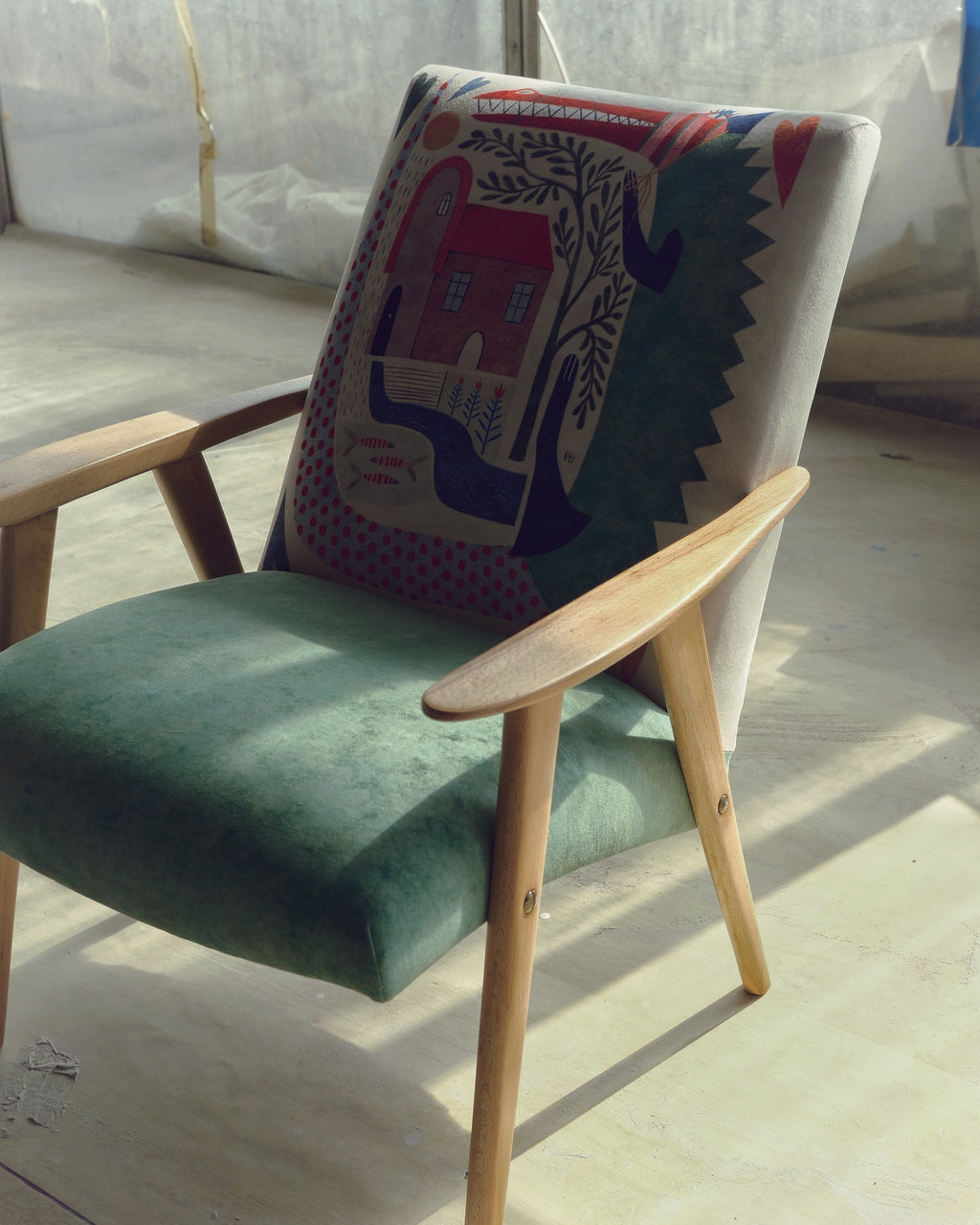 Green chair with a decorative back featuring an elephant design on a light wooden floor.