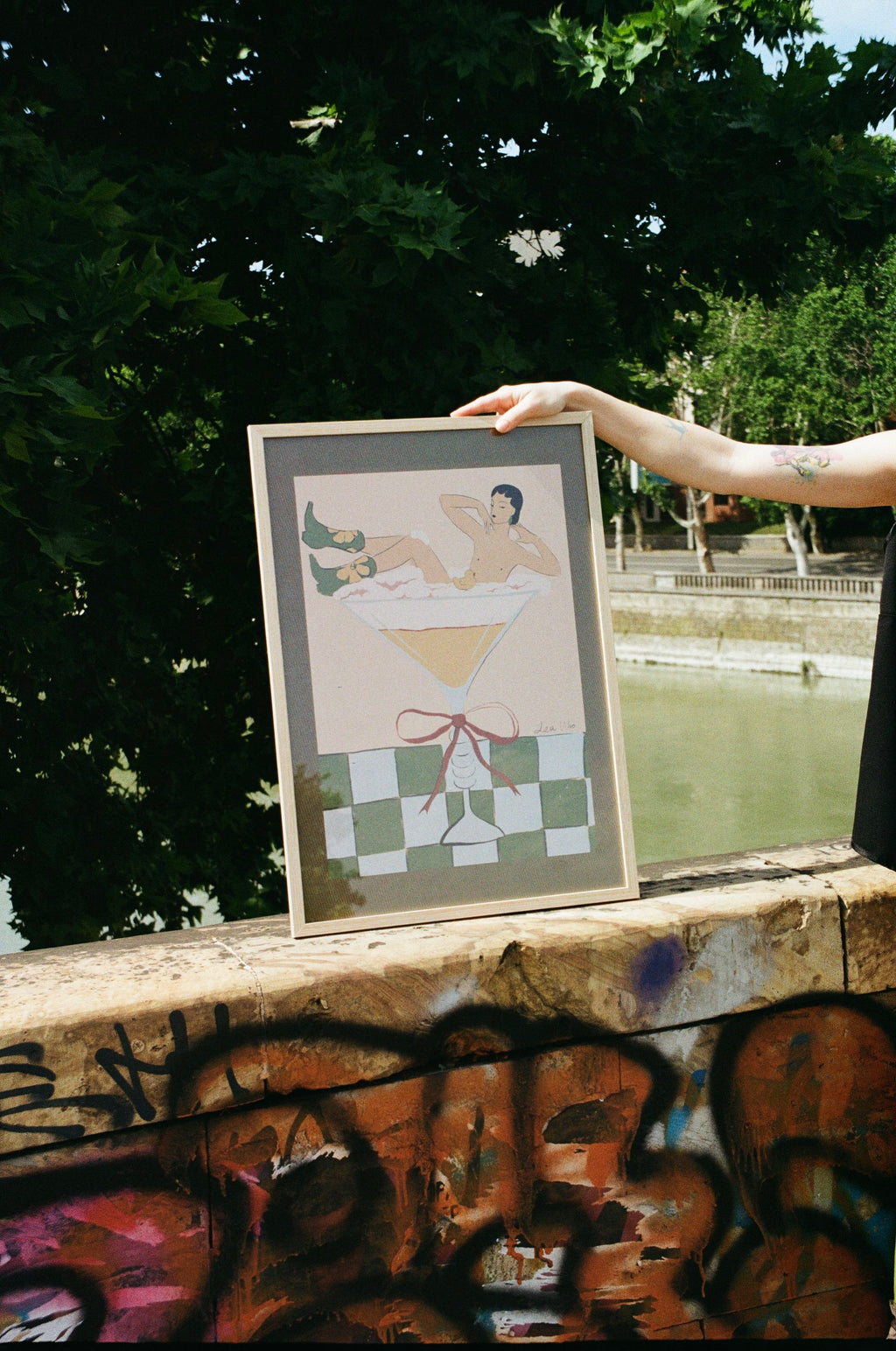 Framed poster of a person in a bathtub held by a person against a trees in the background.