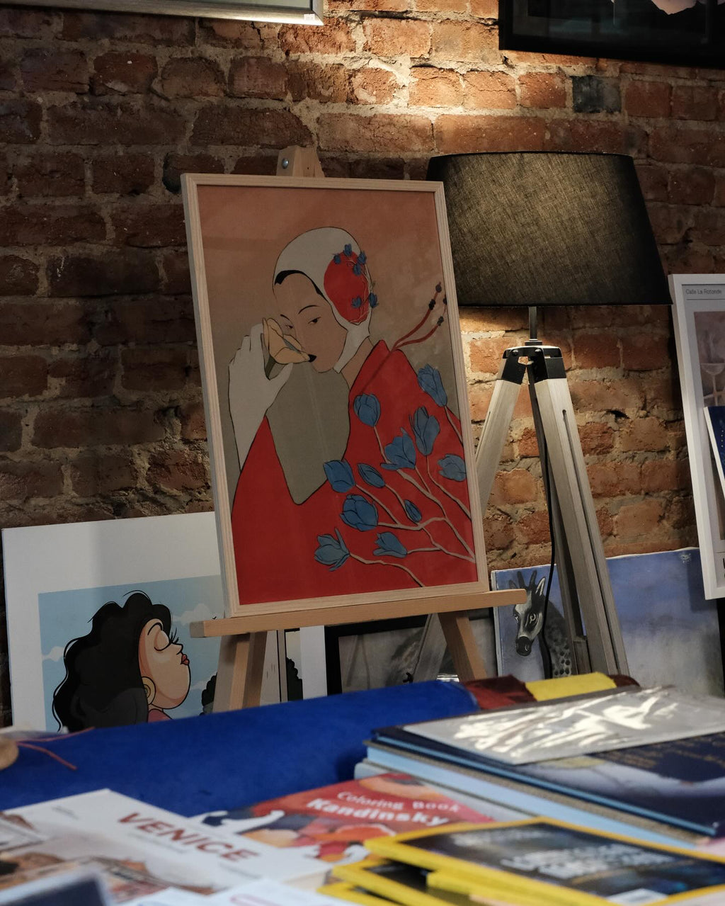 Artistic depiction of a woman with flowers on an easel against a brick wall.
