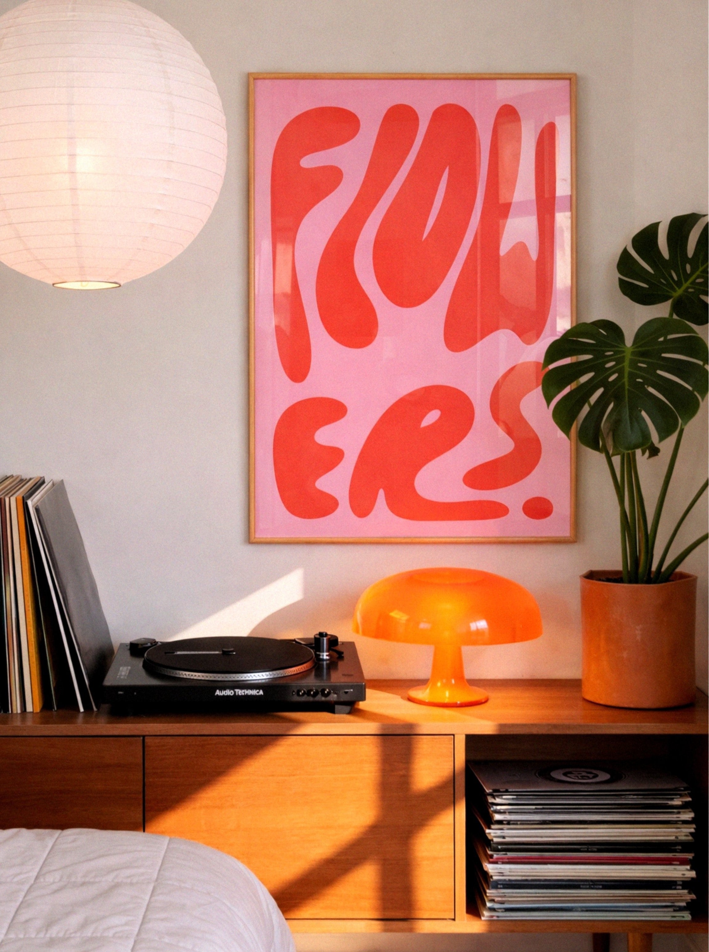 wood framed poster by DAE in the bedroom, next to plant
