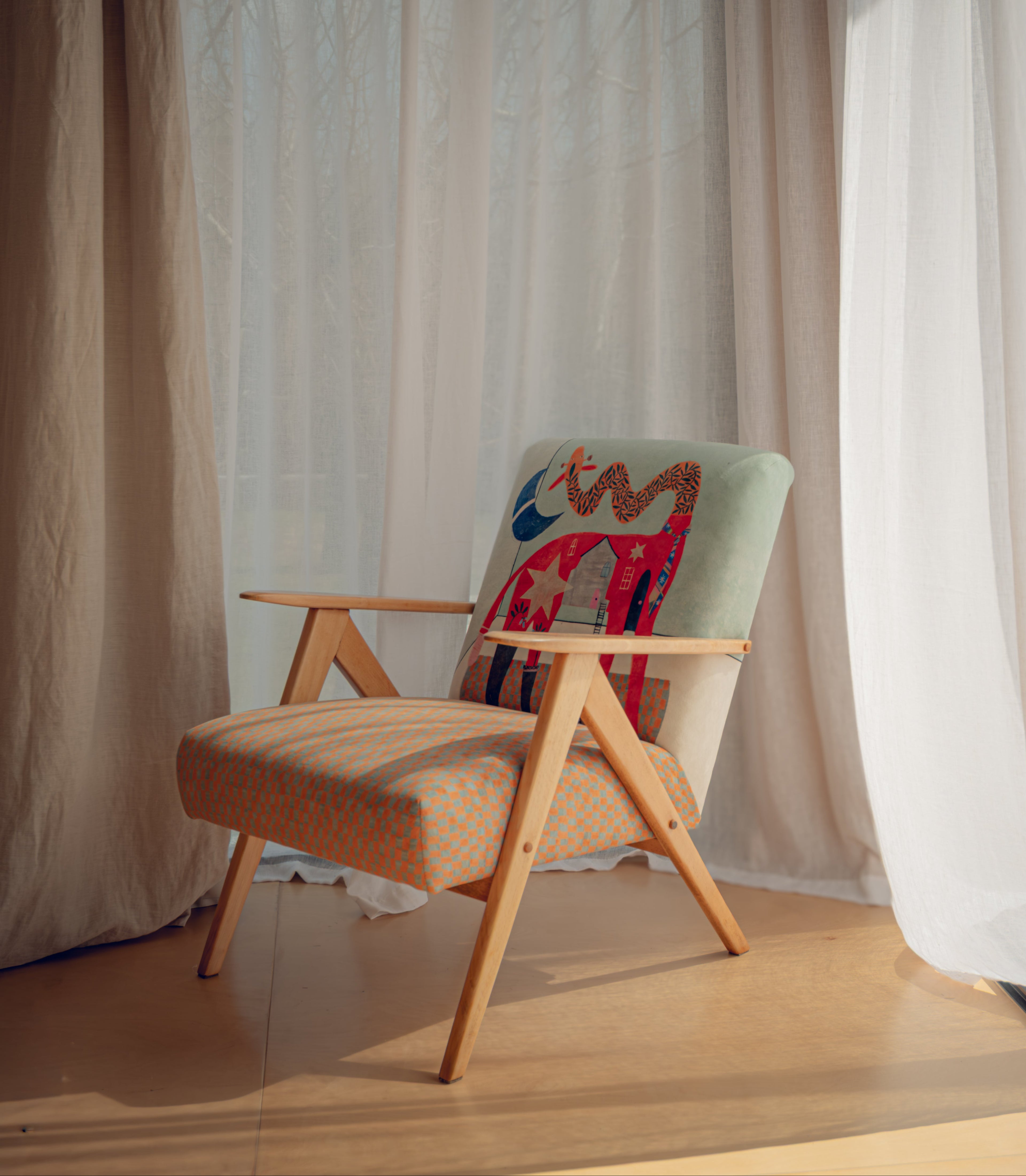 Wooden armchair with a colorful cushion against a white curtain backdrop