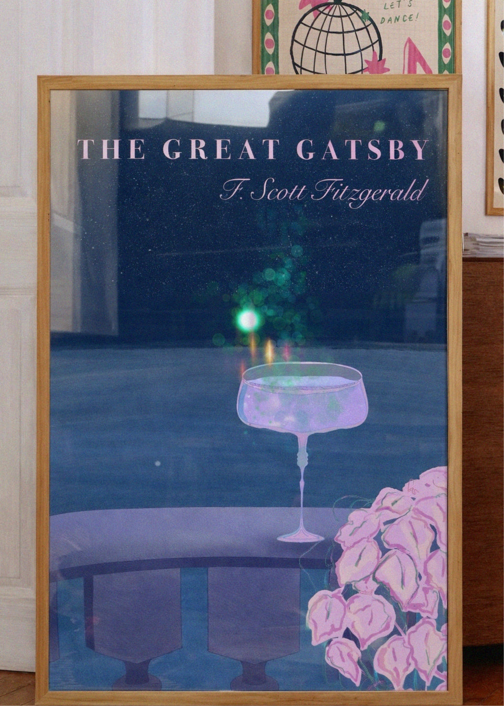 Framed poster of 'The Great Gatsby' with a glass and flowers on a table.