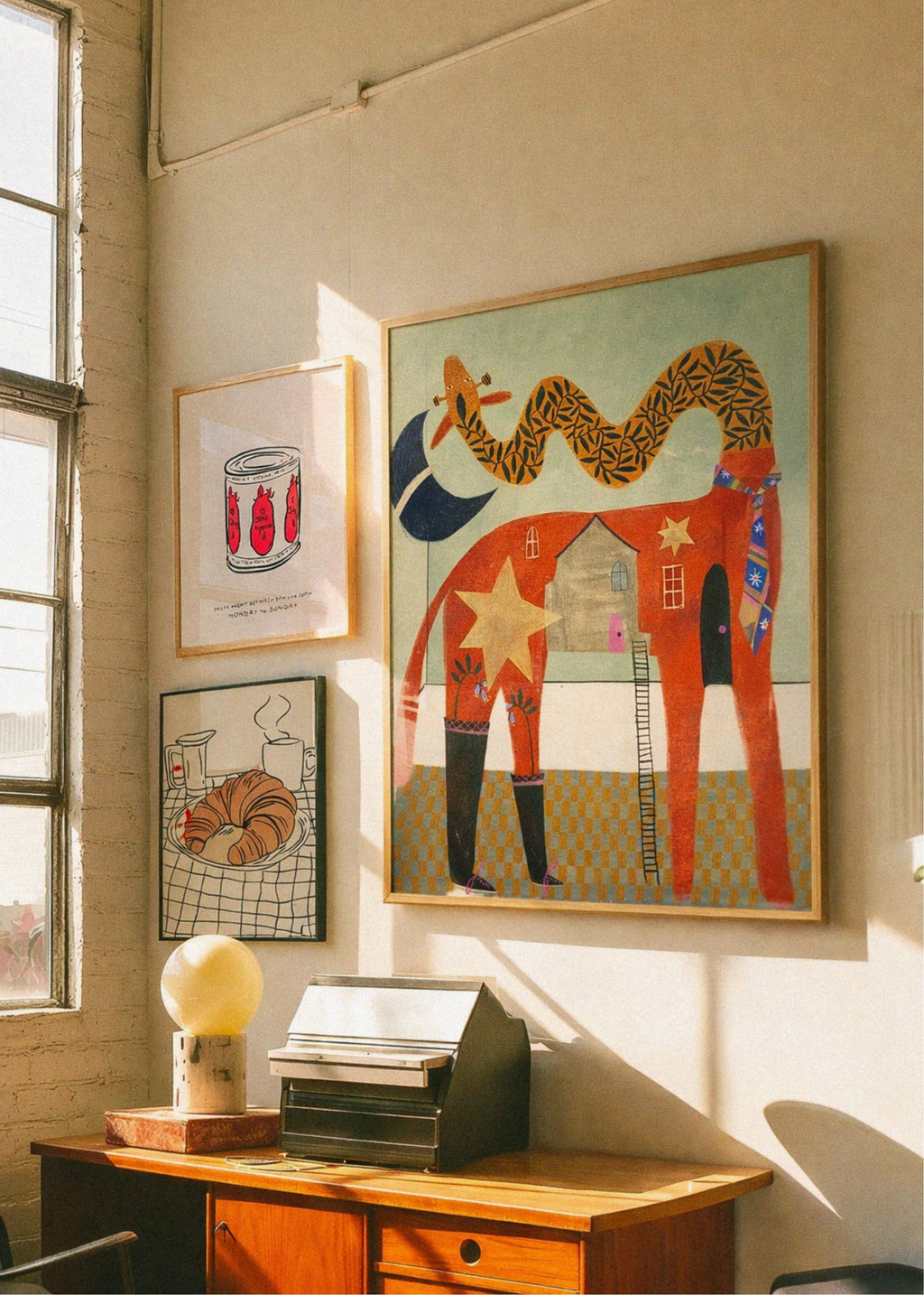 Decorative office with framed artwork on the wall and a wooden desk.