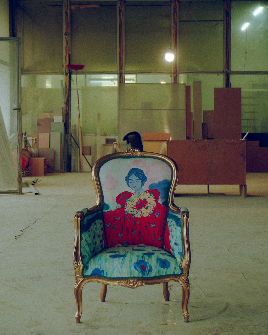 An ornate chair with featuring a painting of a woman, situated in a spacious room with low lighting.