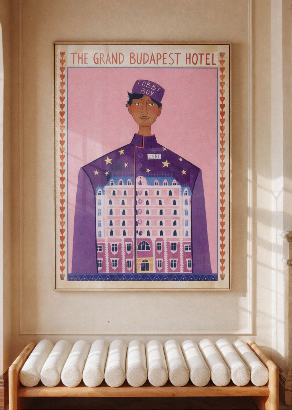 Poster of a character from 'The Grand Budapest Hotel' on a wall above a bench.