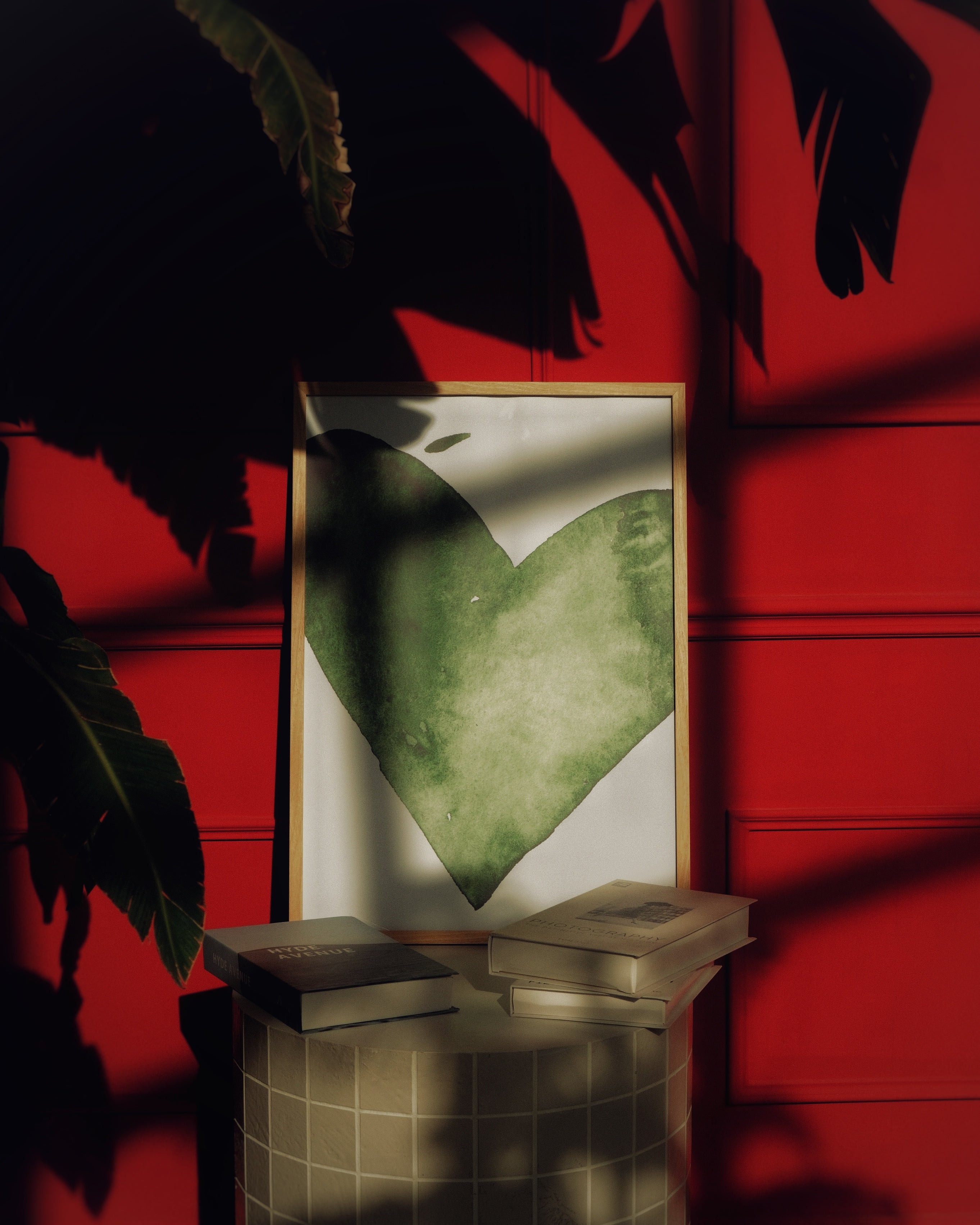 Framed artwork with a green heart design on a red wall