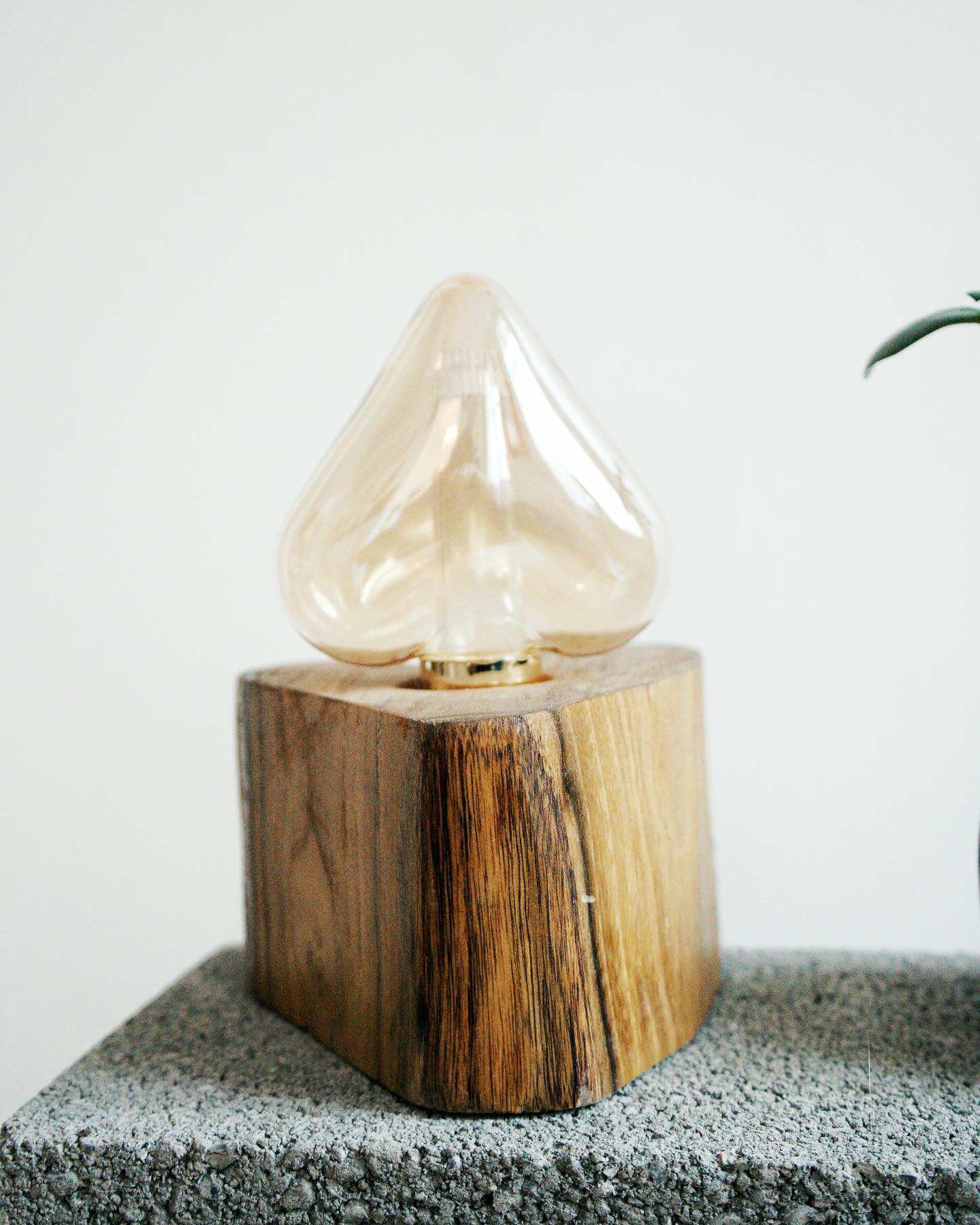 Table lamp with wooden base and clear glass shade on a textured surface