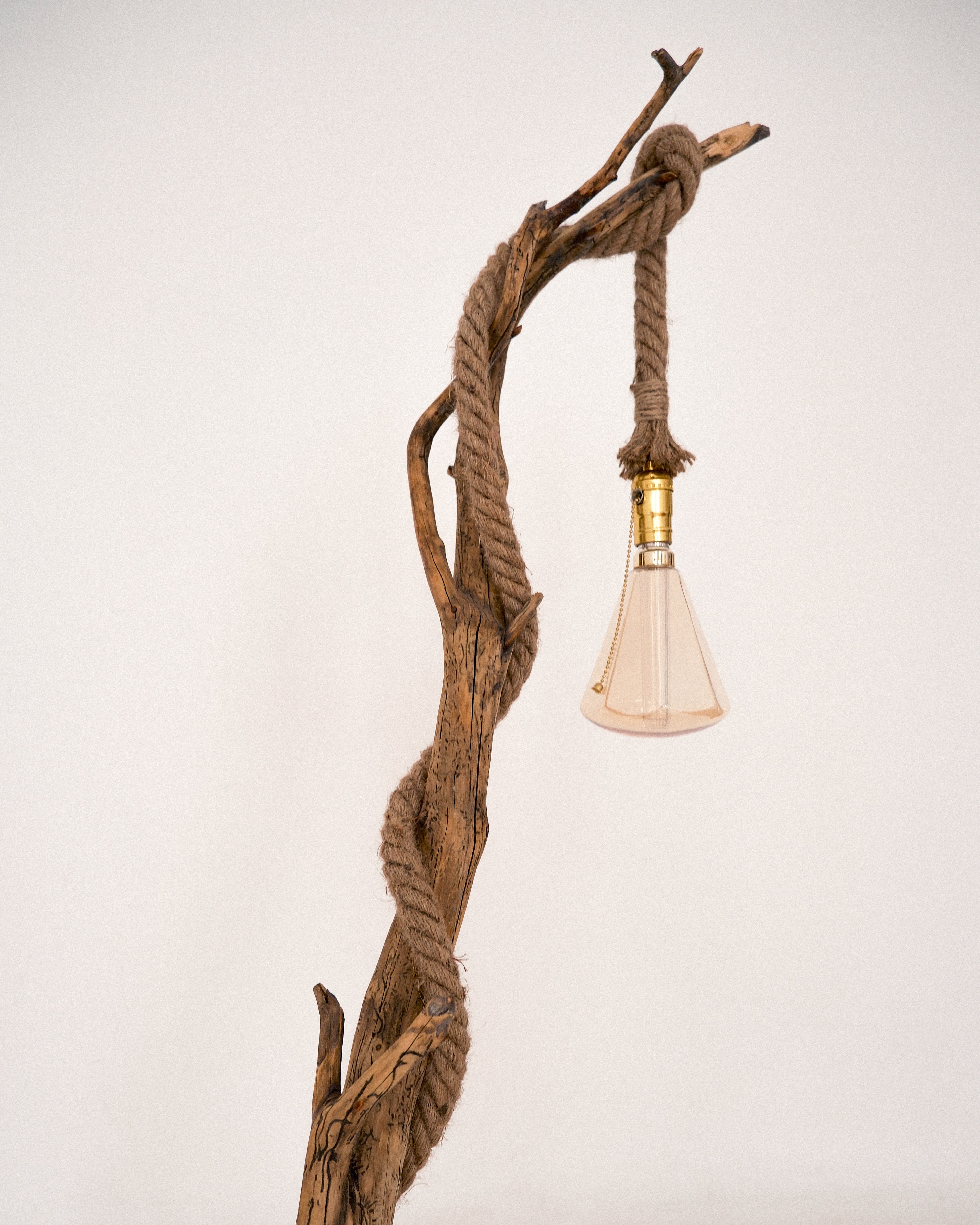 Lamp with natural wood and rope design on a plain background