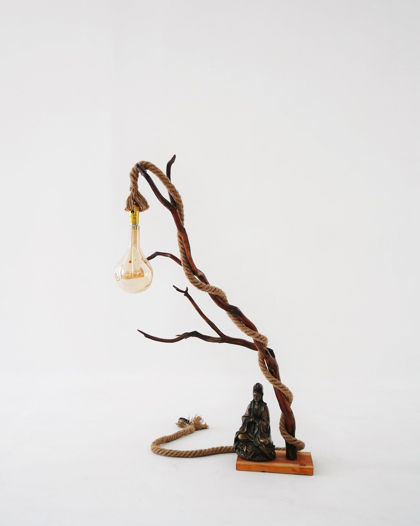 Decorative lamp with twisted rope and small statue on a white background