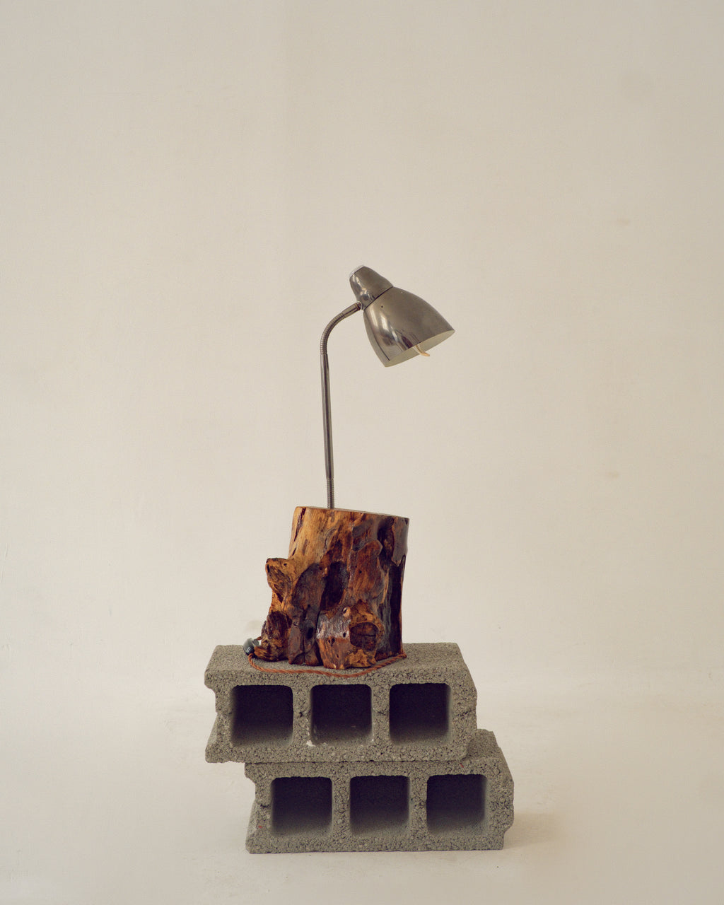 Small lamp on a concrete block with a natural wood base against a plain background