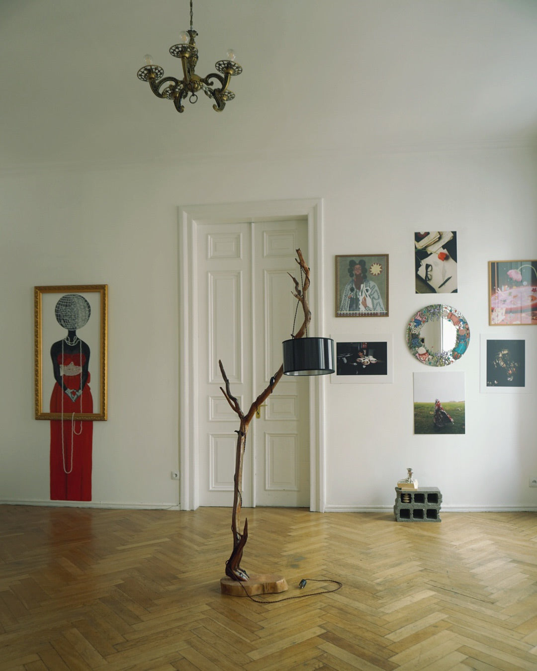 Room with artistic wall decorations, a lamp on a wooden base, and a chandelier.