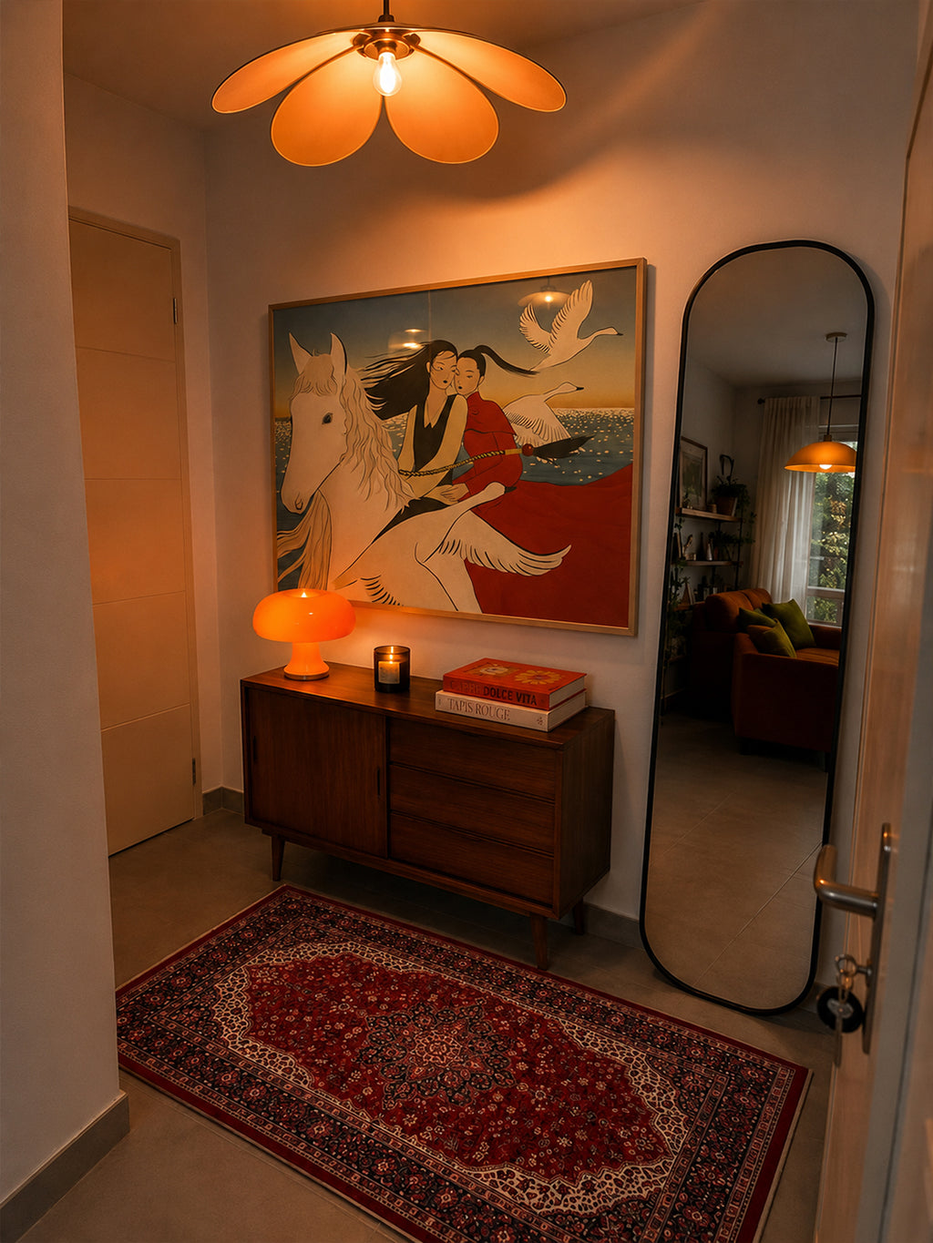 A warm, cozy interior hallway featuring a large framed art print of a woman on a white horse, displayed above a wooden sideboard. The scene is illuminated by a distinctive flower-shaped ceiling light and an orange table lamp, with a red patterned rug on the floor and a tall black-framed mirror on the right.