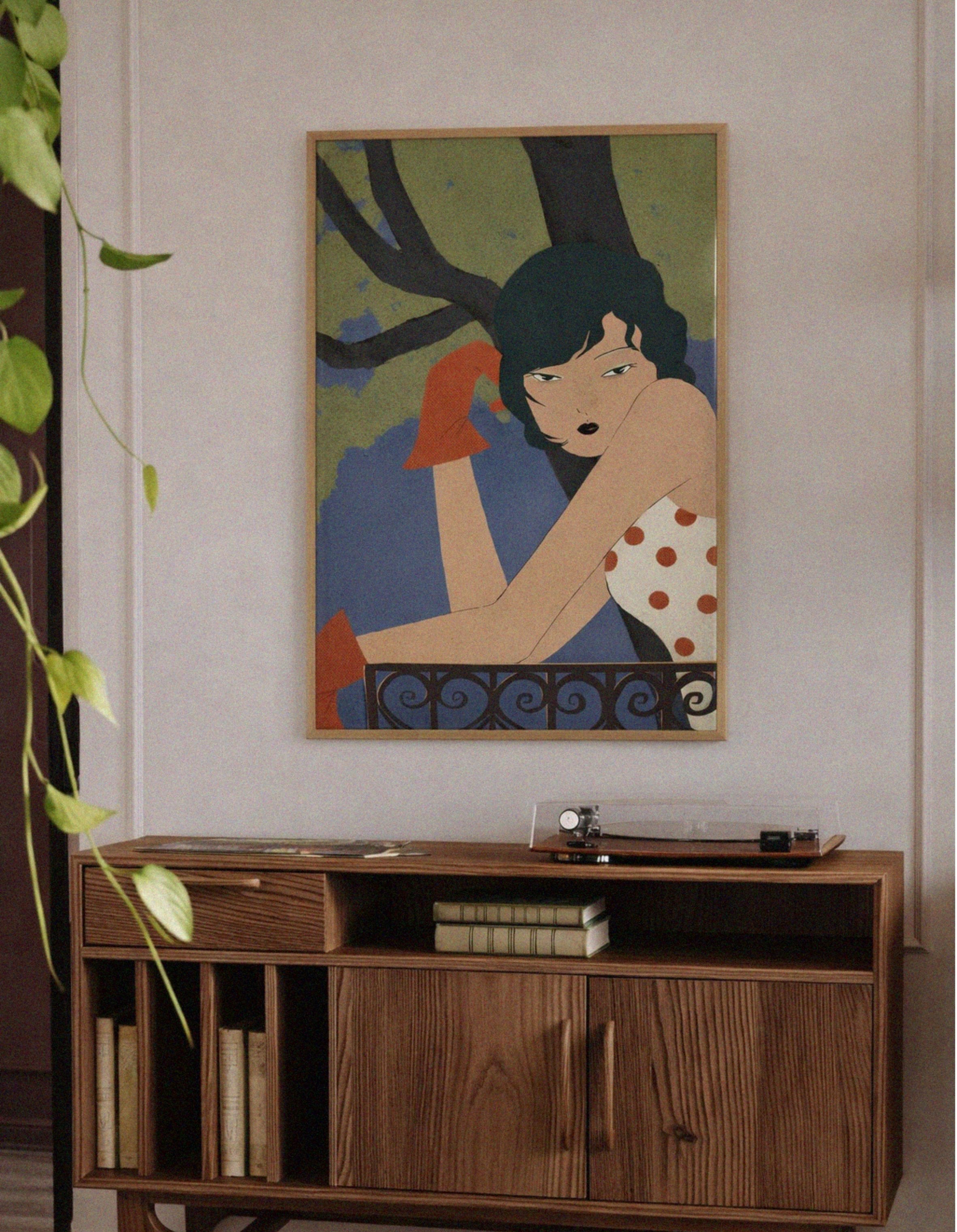 Wooden cabinet with a framed artwork of a woman in a polka dot dress on a wall.