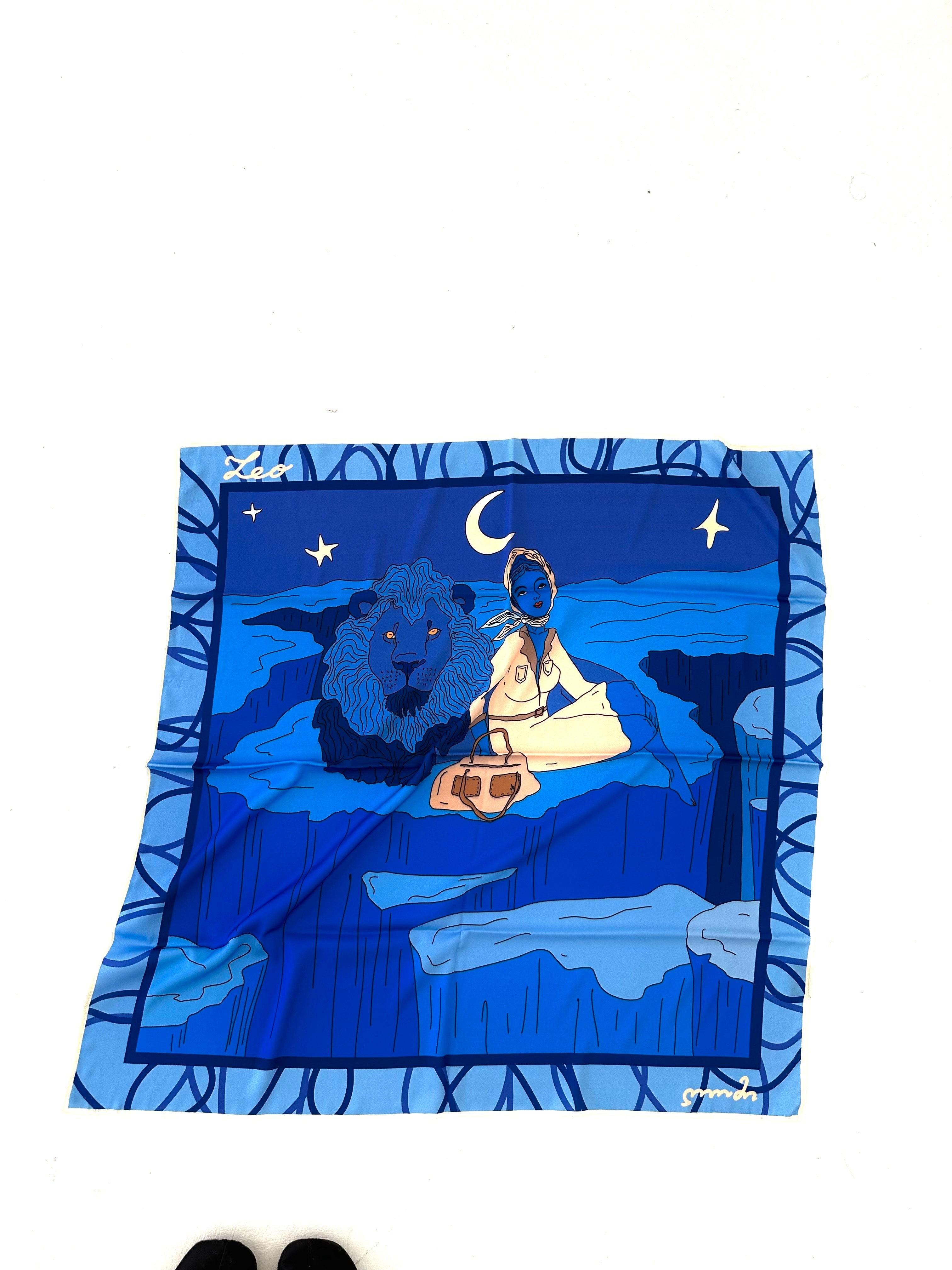 Decorative blue pillow with a lion and pyramid design on a white background, Leo zodiac art silk scarf illustrated by Anano Kevanishvili in bold blue and gold tones