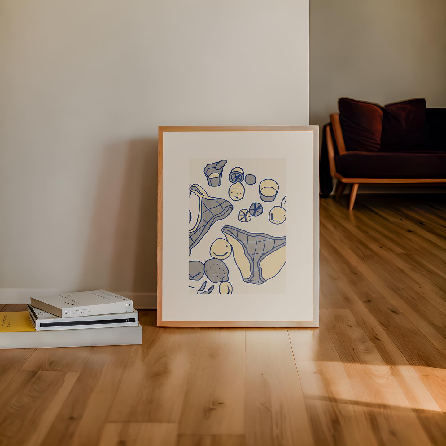 Framed poster by DAE on a wooden floor with books and a couch in the background