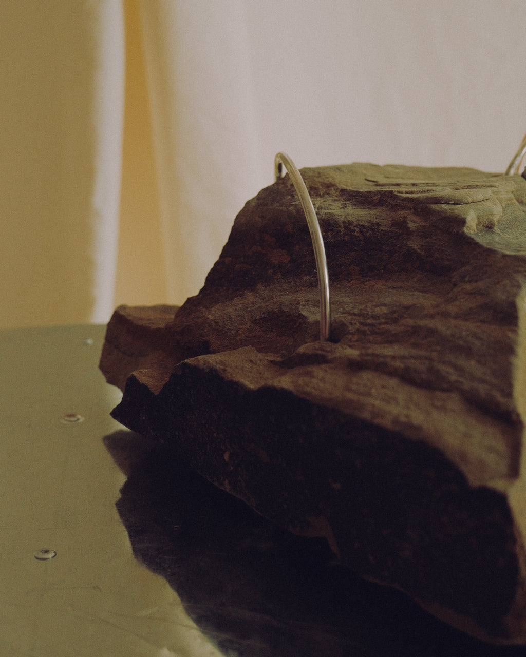 Close-up of the natural stone base of the handmade “Loop” lamp, detailed with curved metal elements.