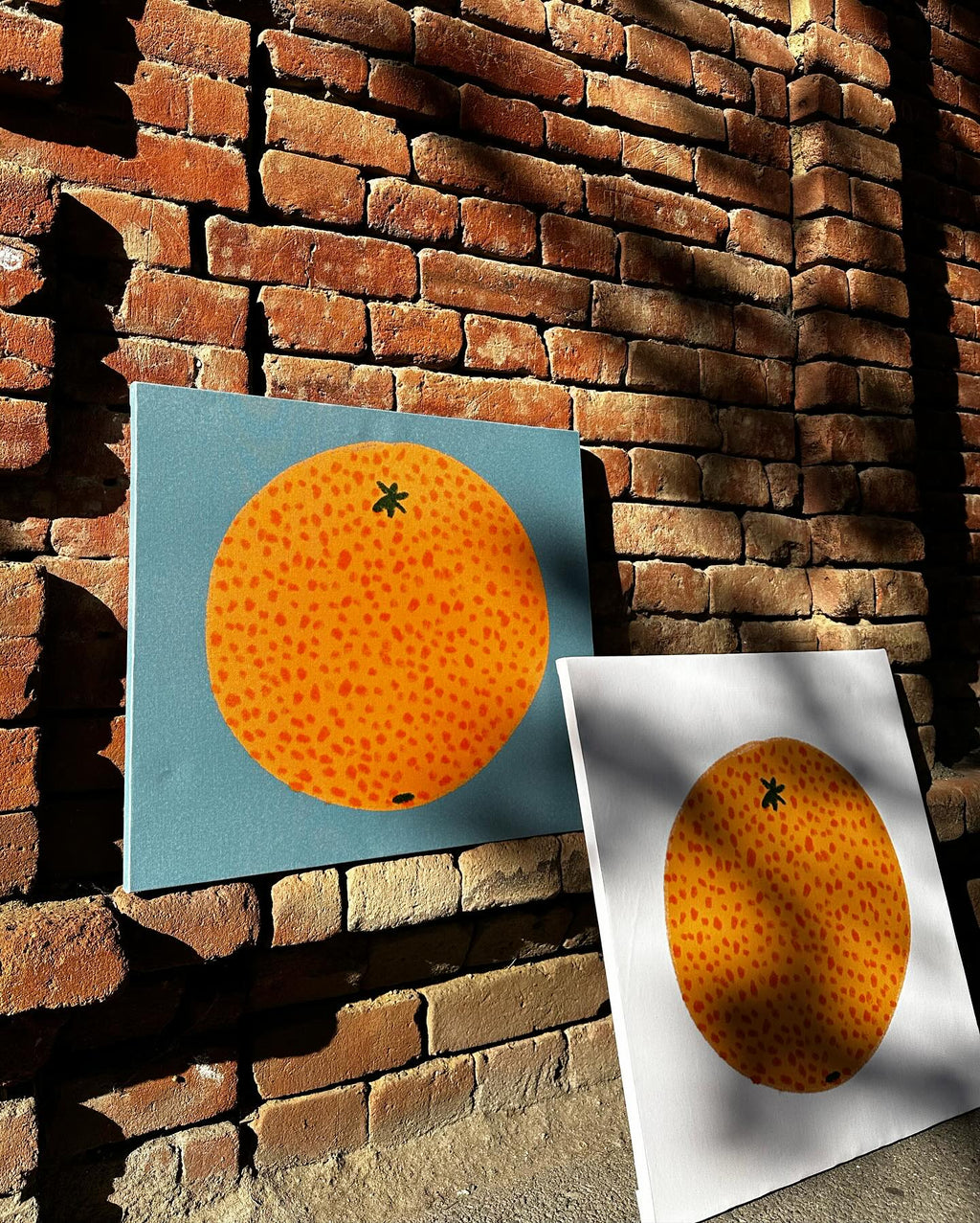 two same designed posters with different color background standing next to each other in street, on the back is brick wall