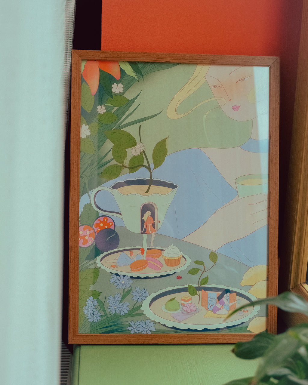 Framed artwork with a stylized illustration of a woman, plants, and a teacup on a colorful background.