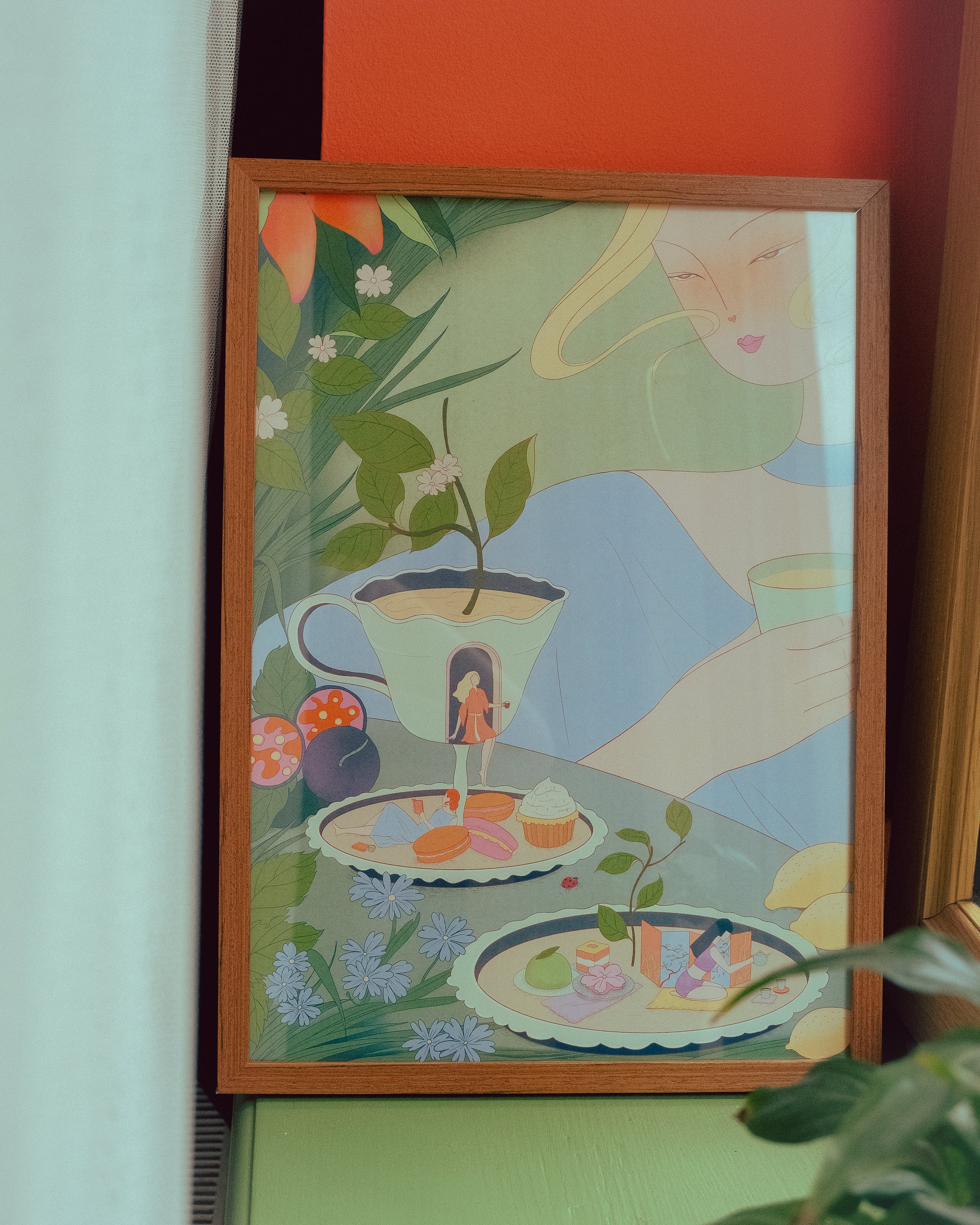 Framed artwork with a stylized illustration of a woman, plants, and a teacup on a colorful background.