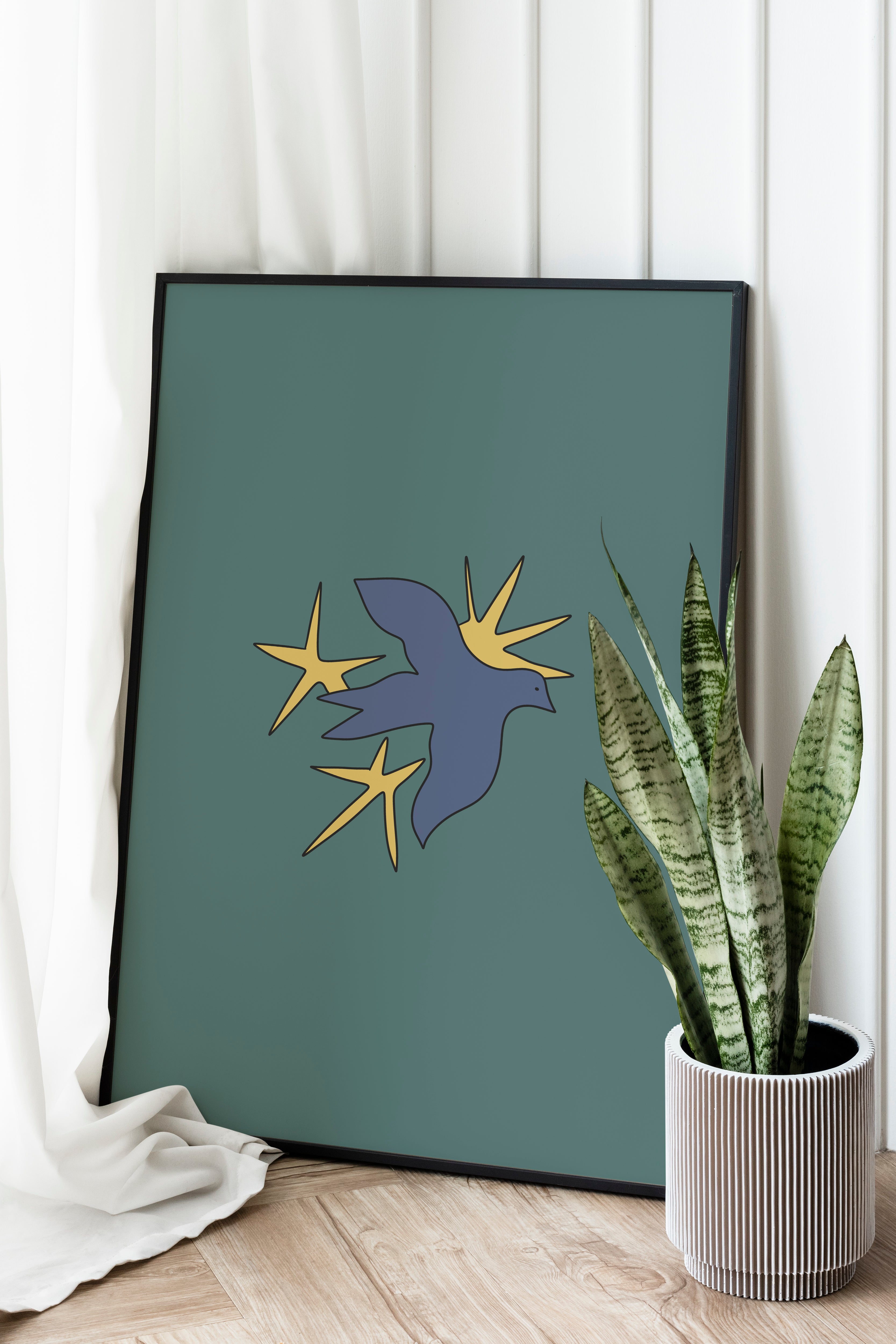 A poster with a minimalist illustration of a bird on a green background, displayed on a wall with a plant beside it.