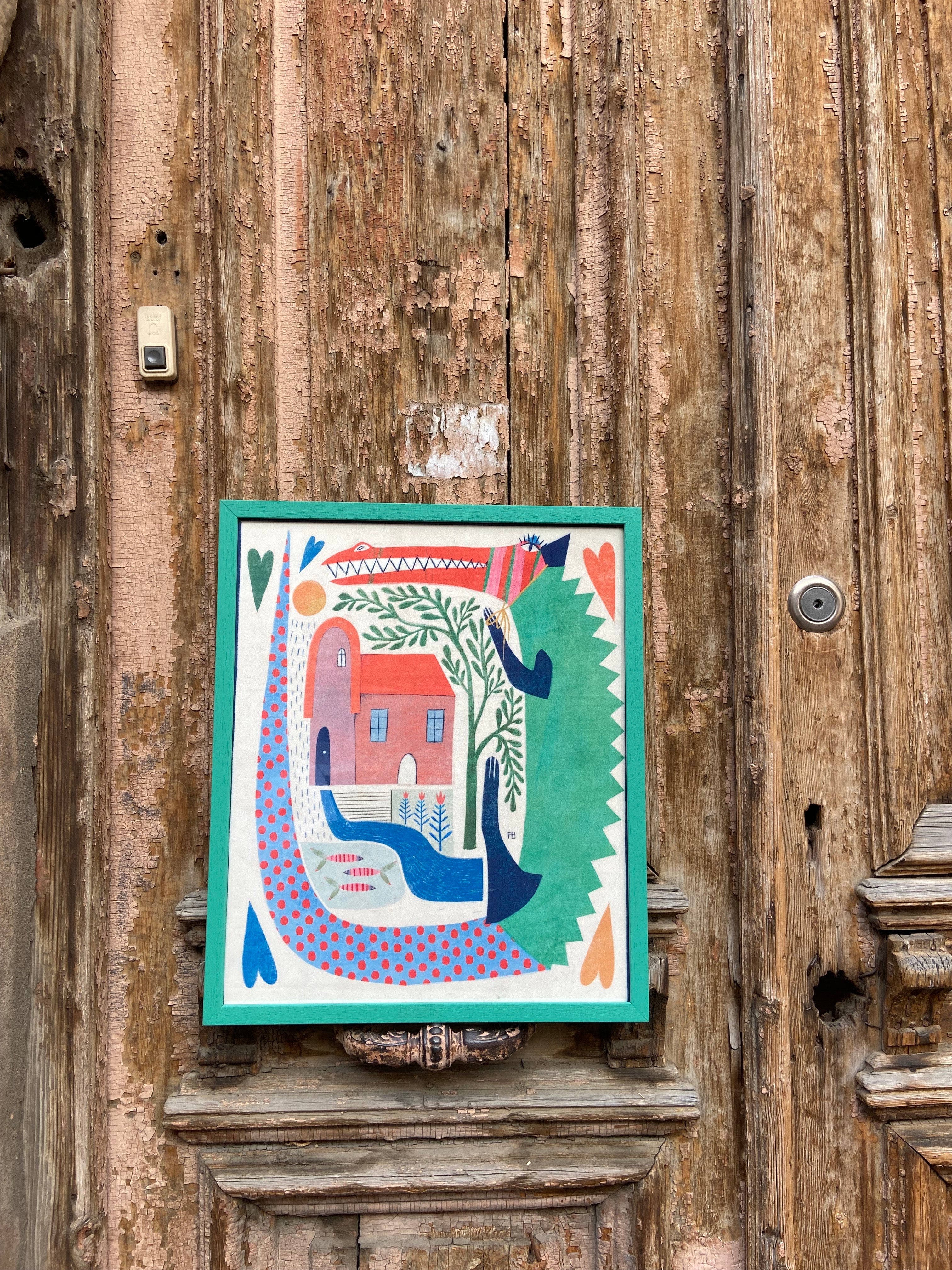 Colorful poster of a house with trees and birds on a wooden wall.