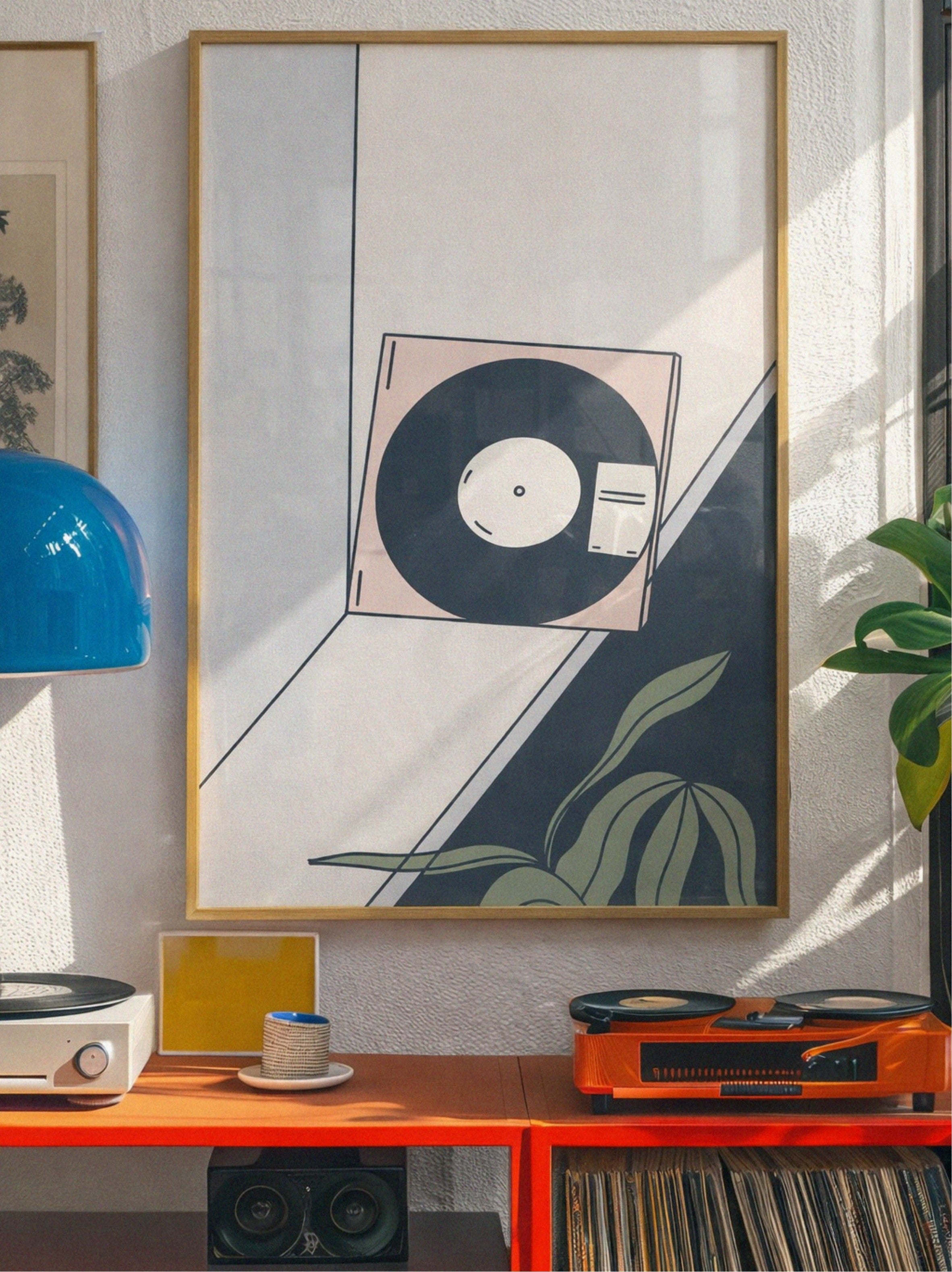 Framed abstract art piece on a wall with a record player and speakers below.