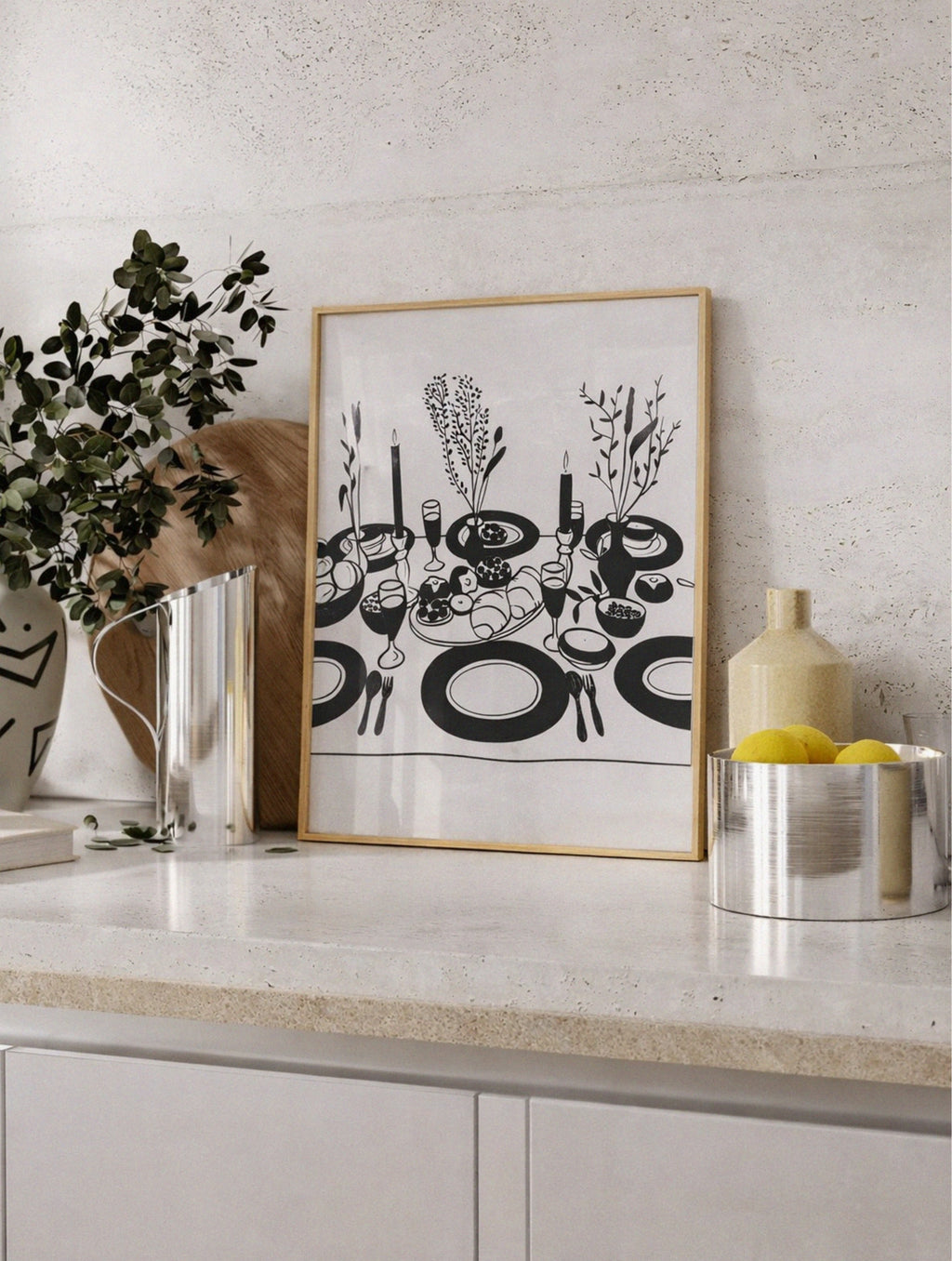 Framed black and white artwork on a kitchen counter with decorative items.