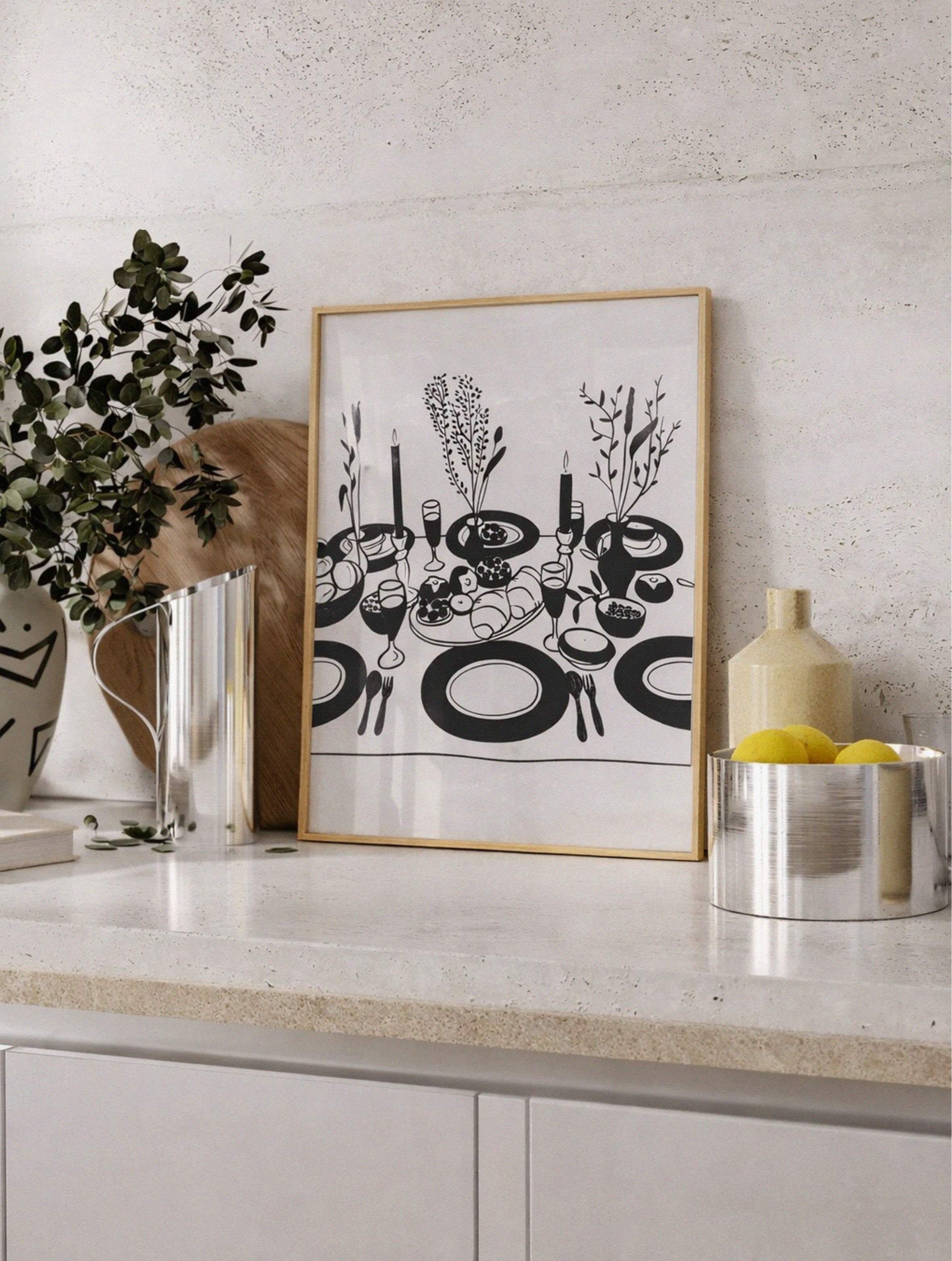 Framed black and white artwork on a kitchen counter with decorative items.