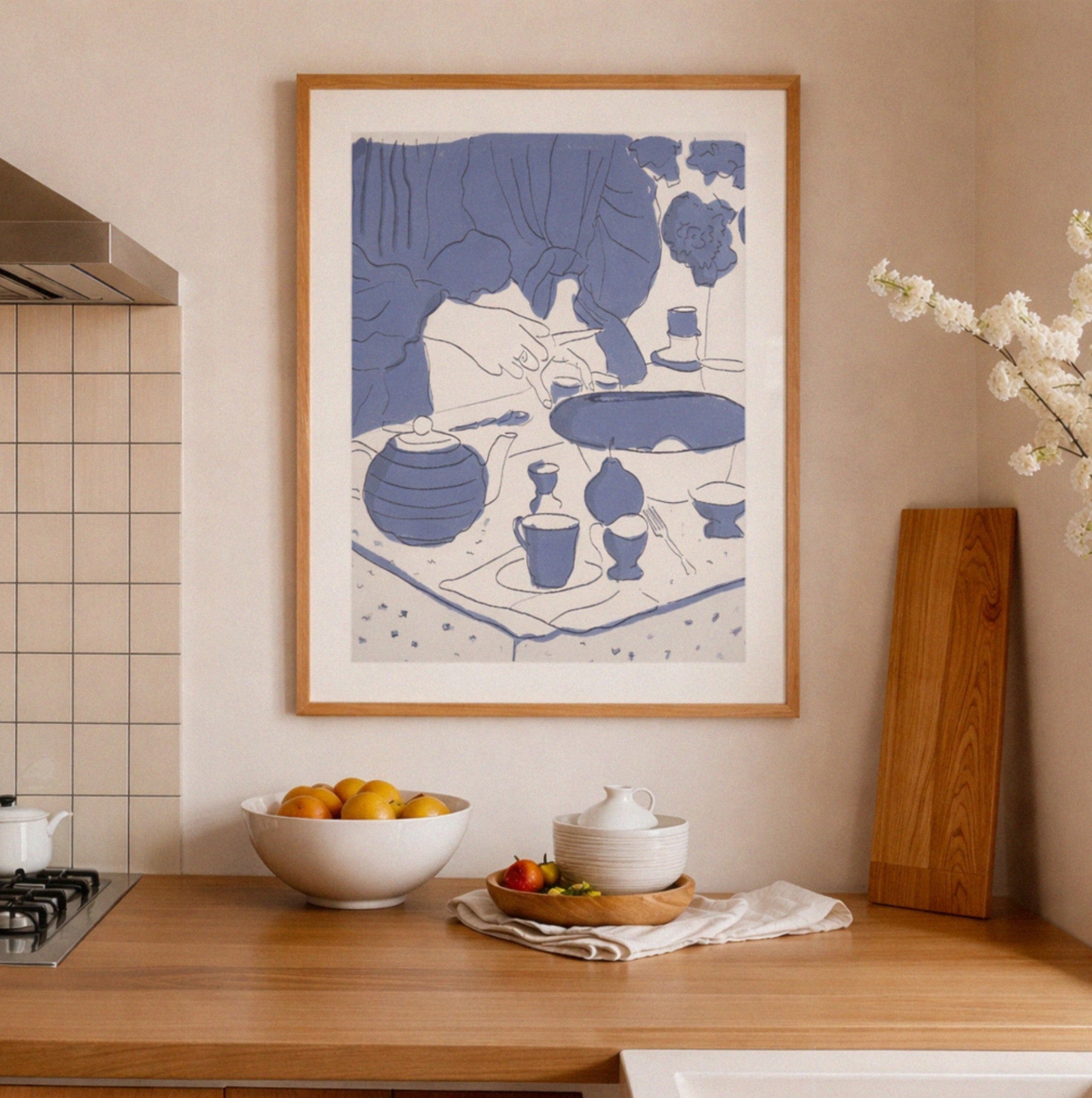Framed artwork in a kitchen with a bowl of fruit and a cutting board.
