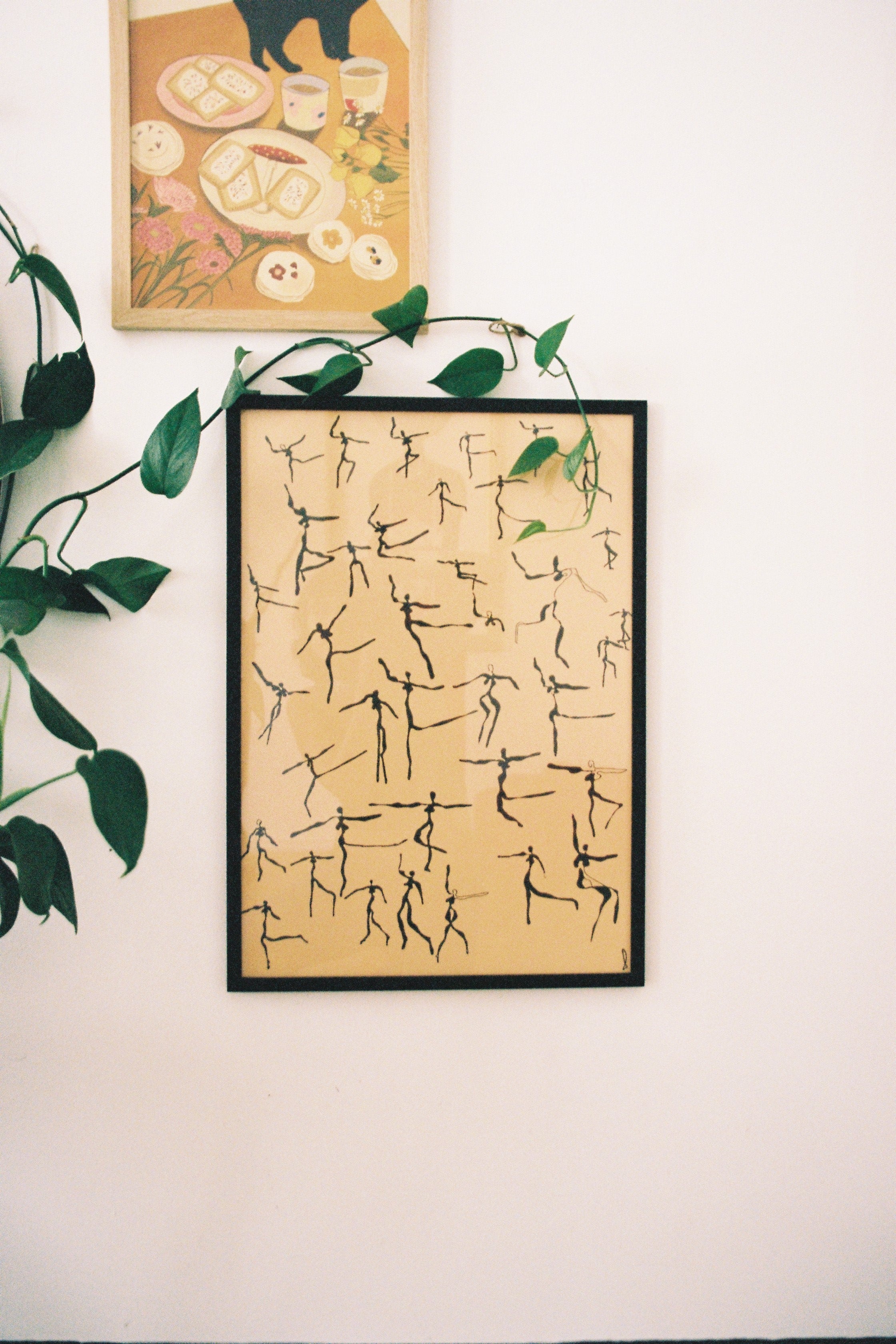 Framed abstract artwork on a wall with a plant