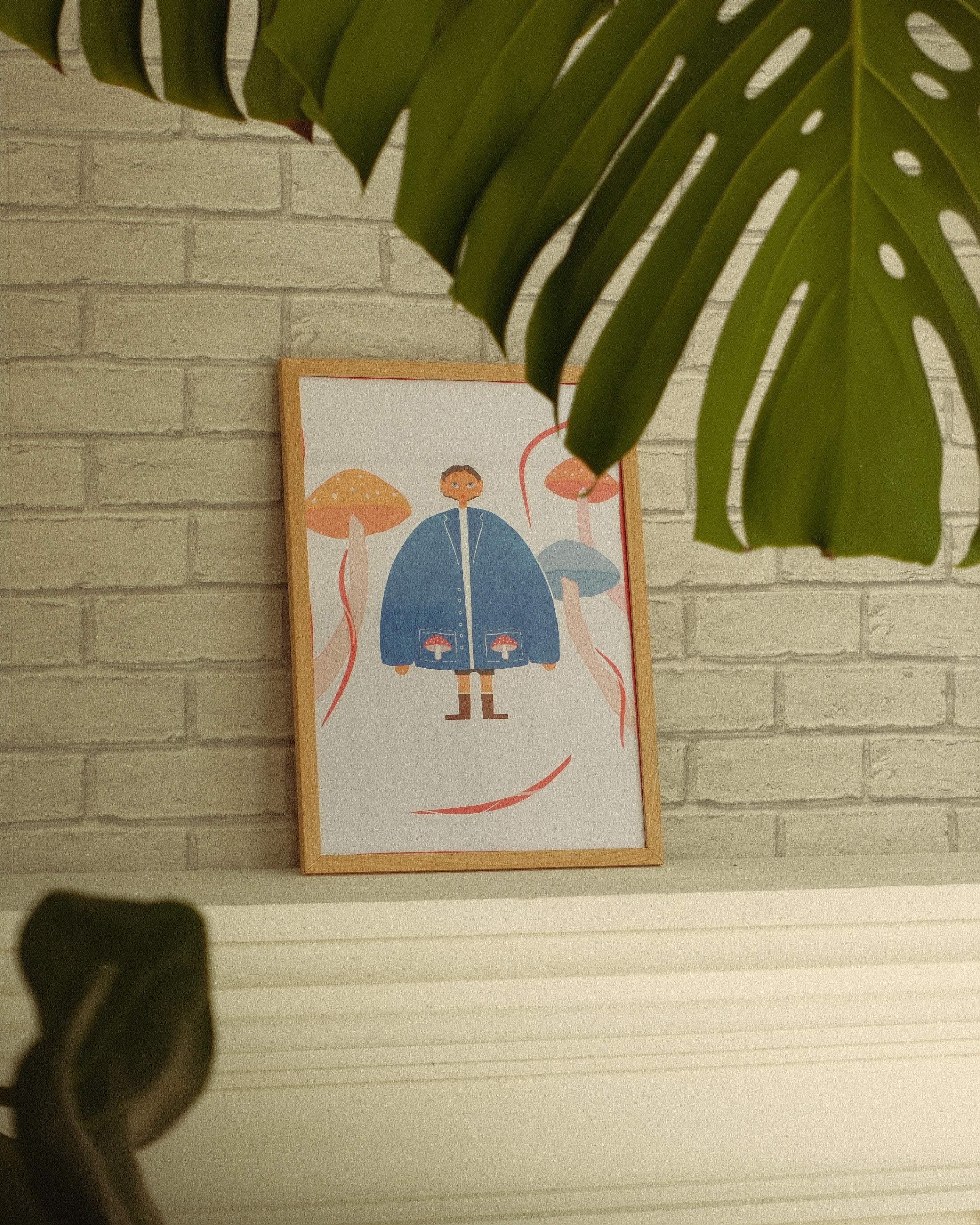 Framed illustration of a person in a blue raincoat on a brick wall.