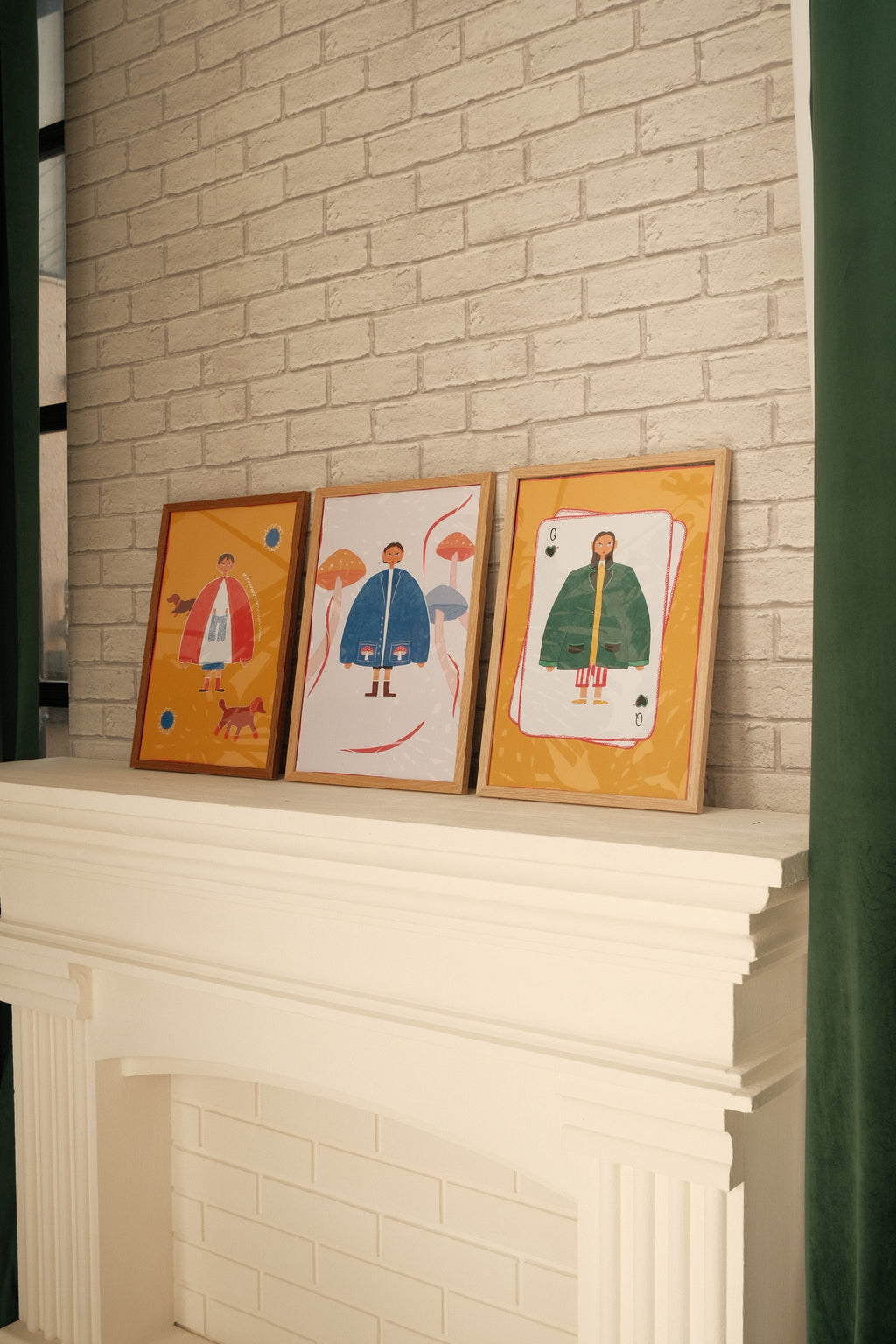 Three framed artworks on a tiled floor next to a stack of white sheets.