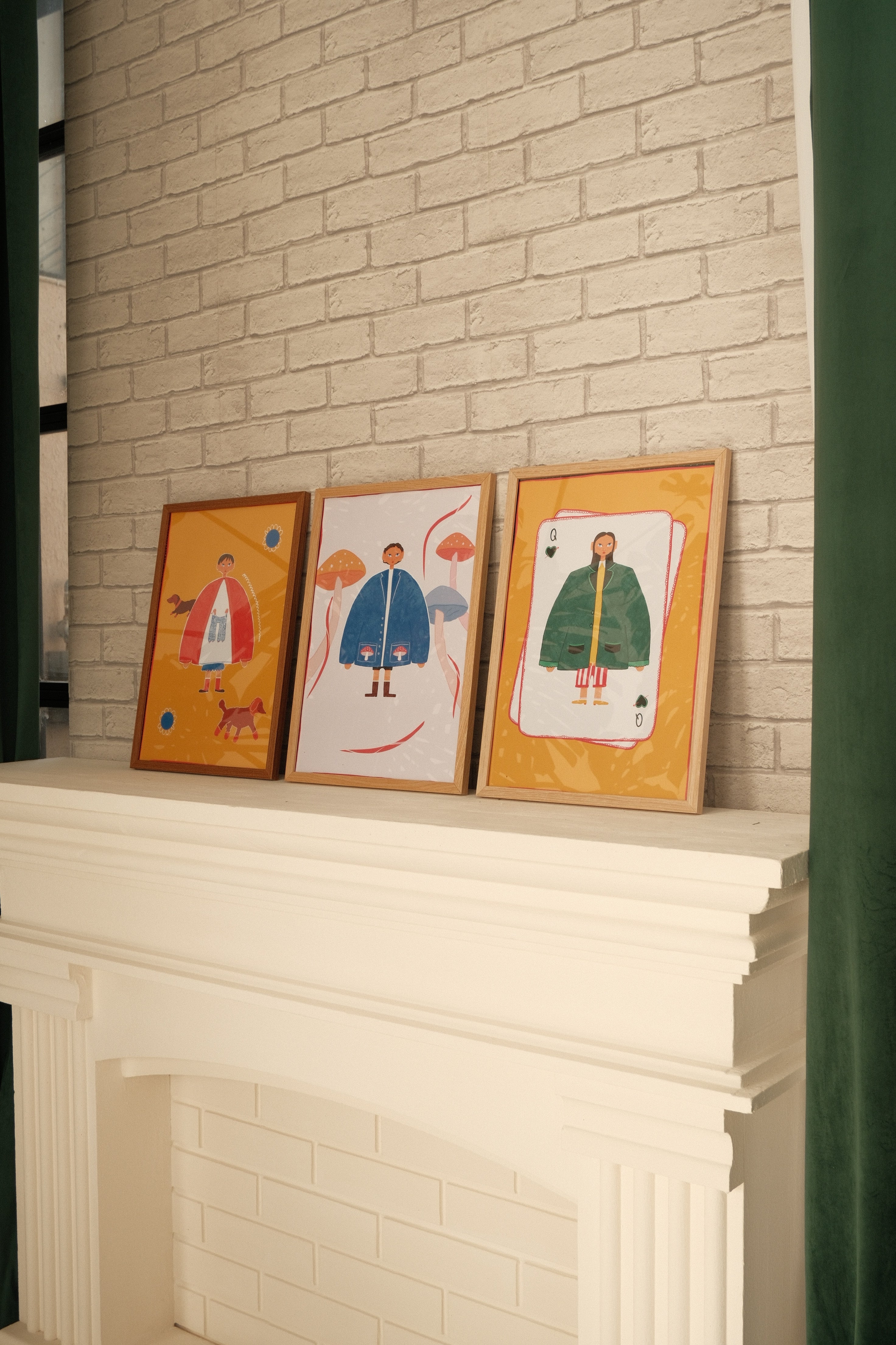 Three framed artworks on a tiled floor next to a stack of white sheets.