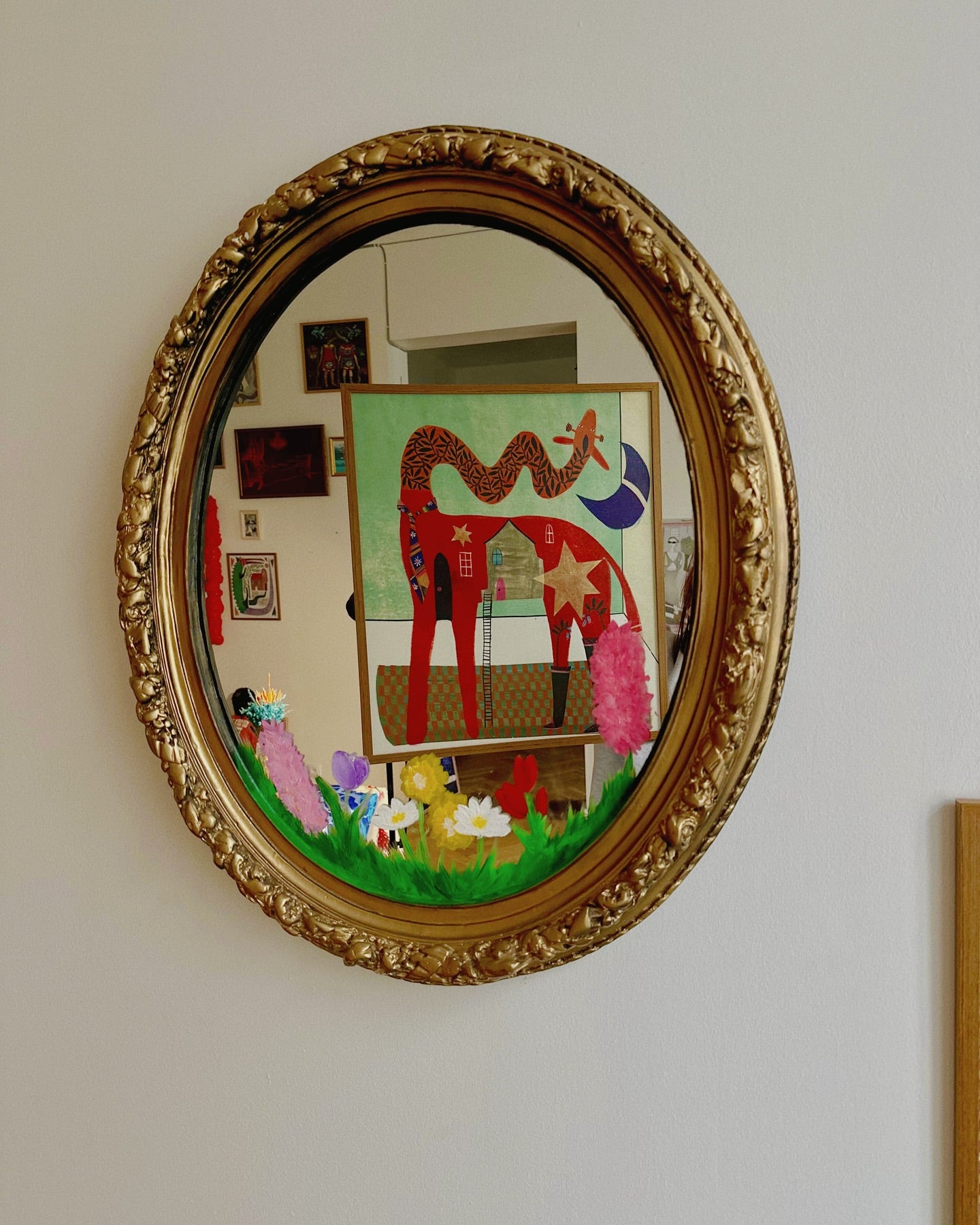 in the miror there is giraffe poster, someone is holding