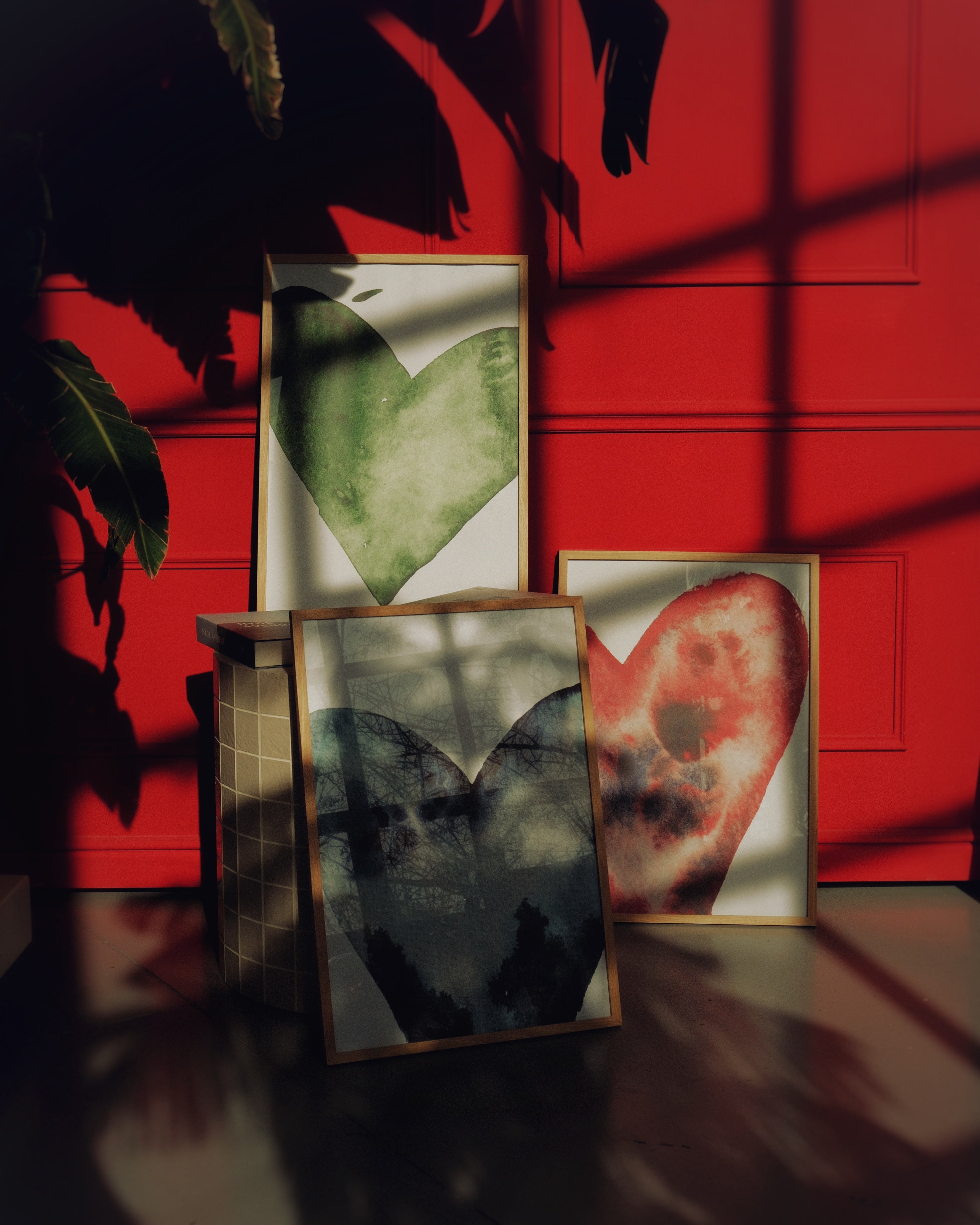 Framed artworks on a table with a red wall background
