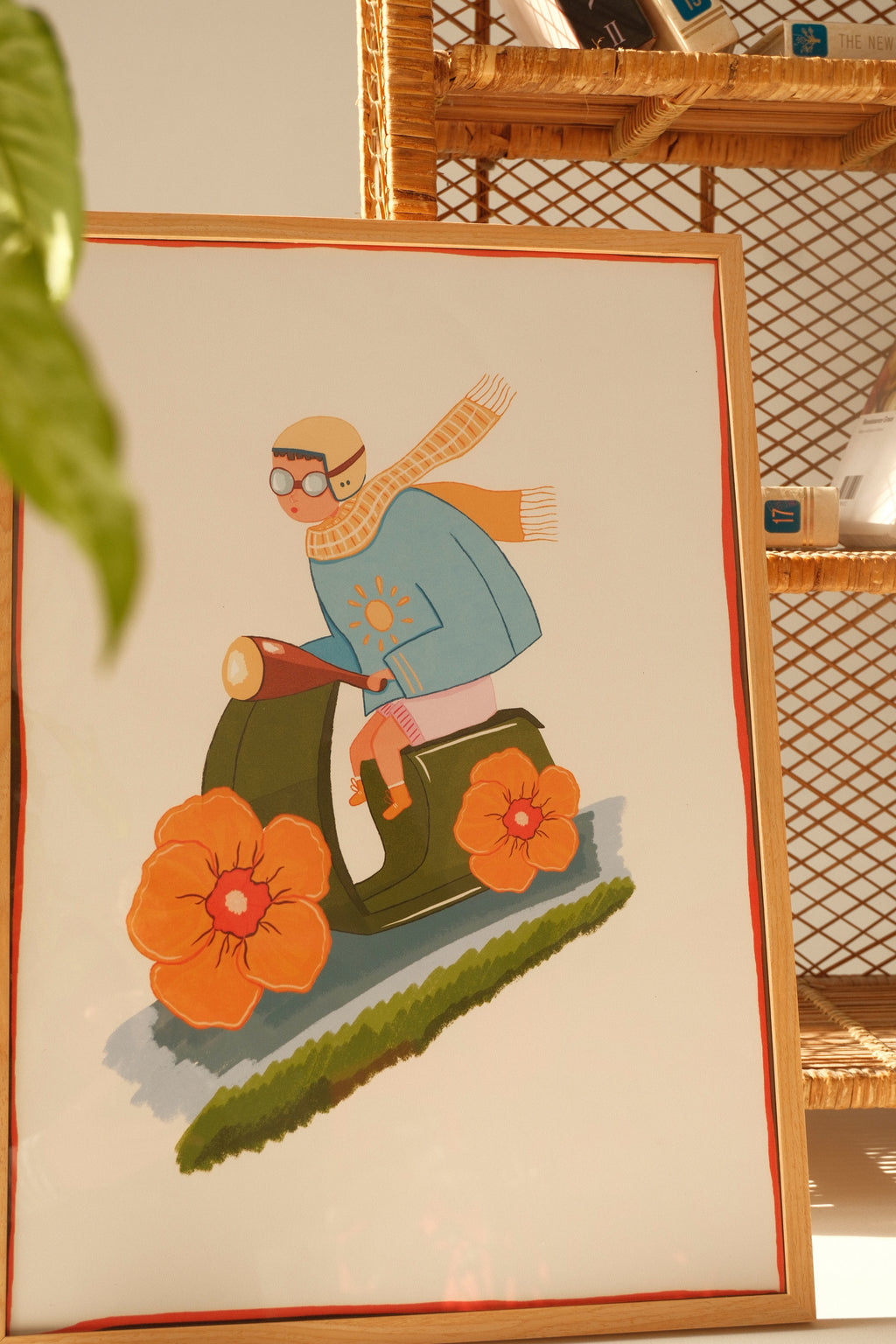 Framed Quiet Ride illustration poster by Tekle Ghvania leaning against a rattan shelf with books and soft natural light.