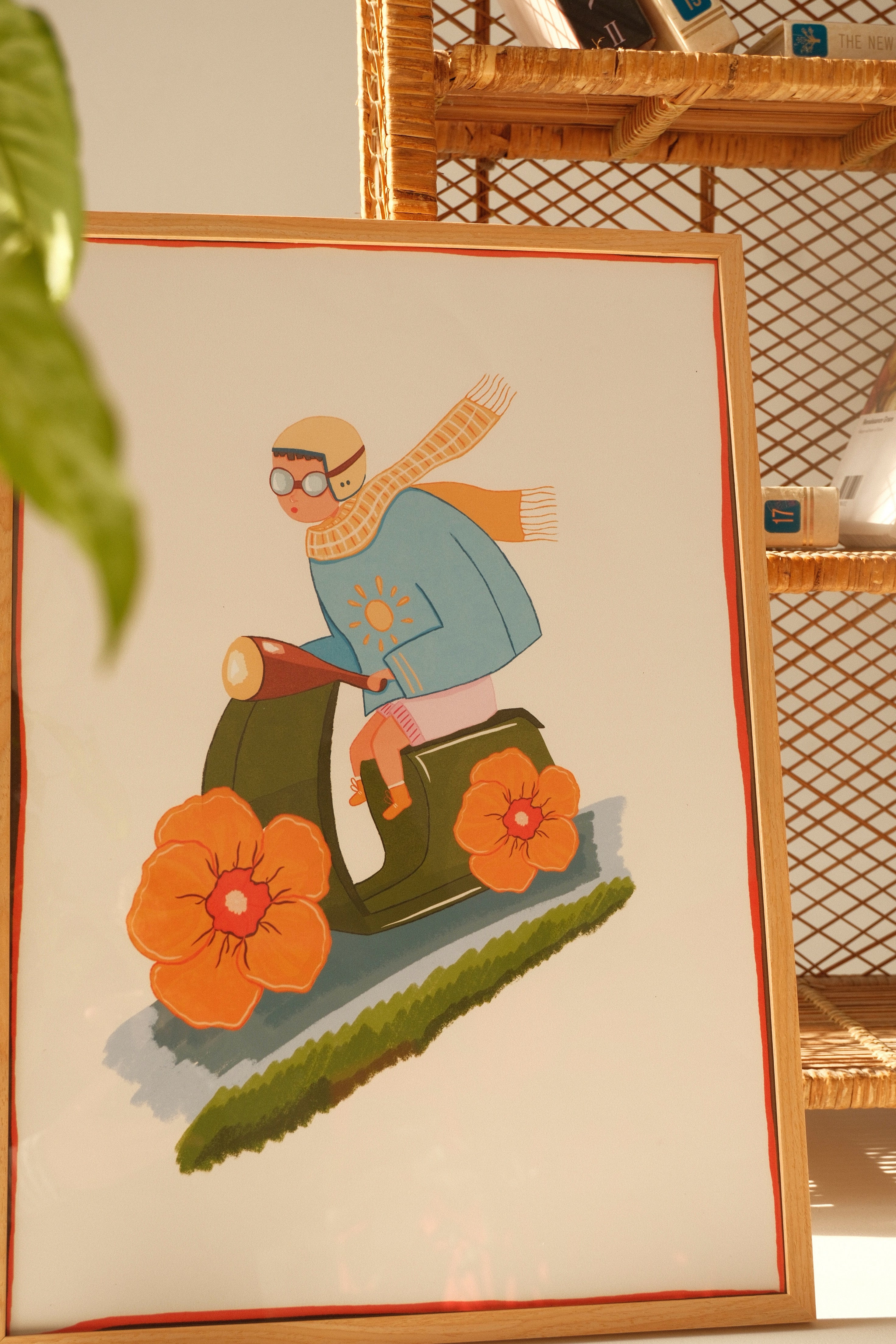 Framed Quiet Ride illustration poster by Tekle Ghvania leaning against a rattan shelf with books and soft natural light.