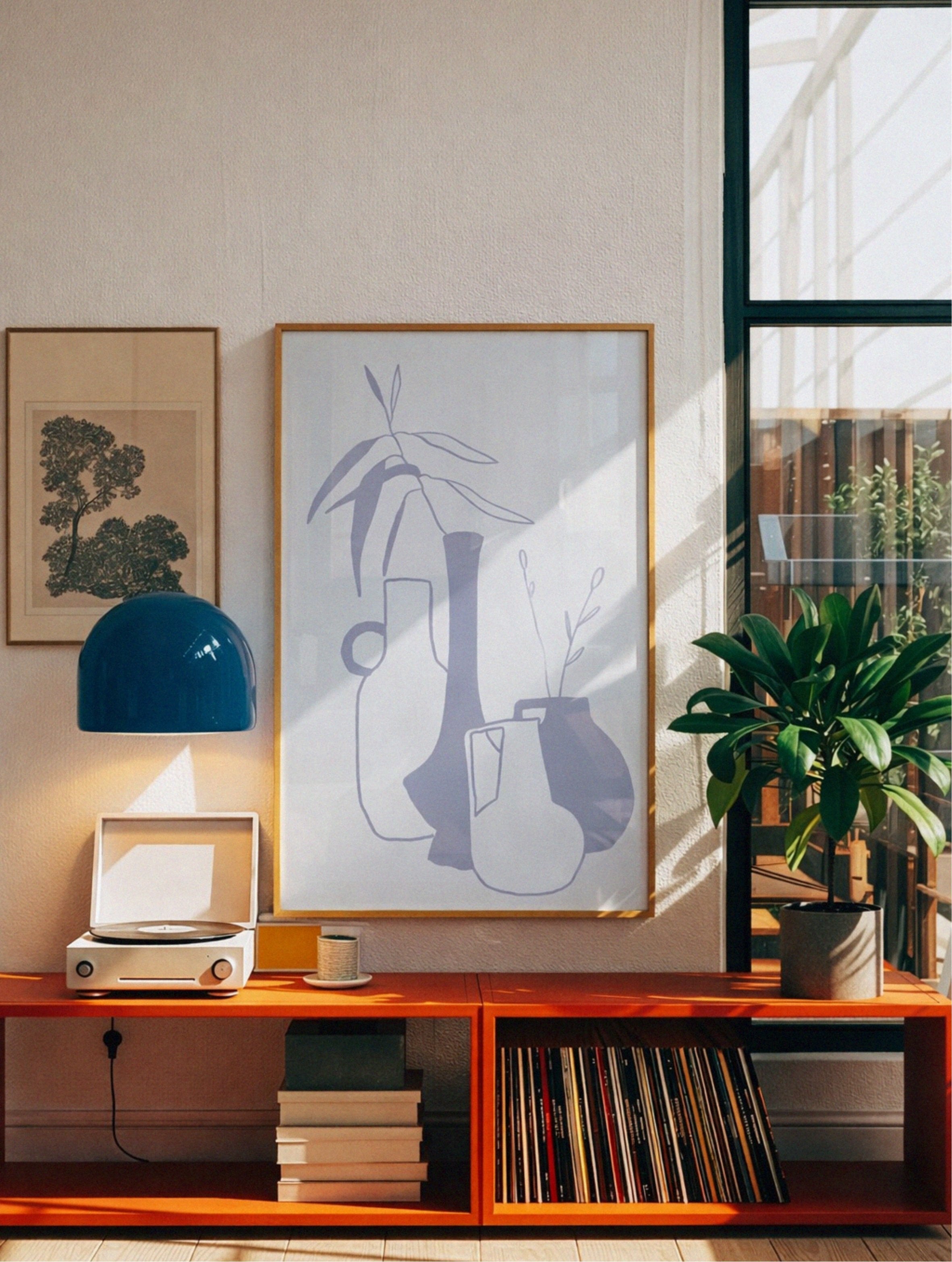 Wooden shelf with books, a plant, and decorative items in a room with natural light, poster by DAE above it