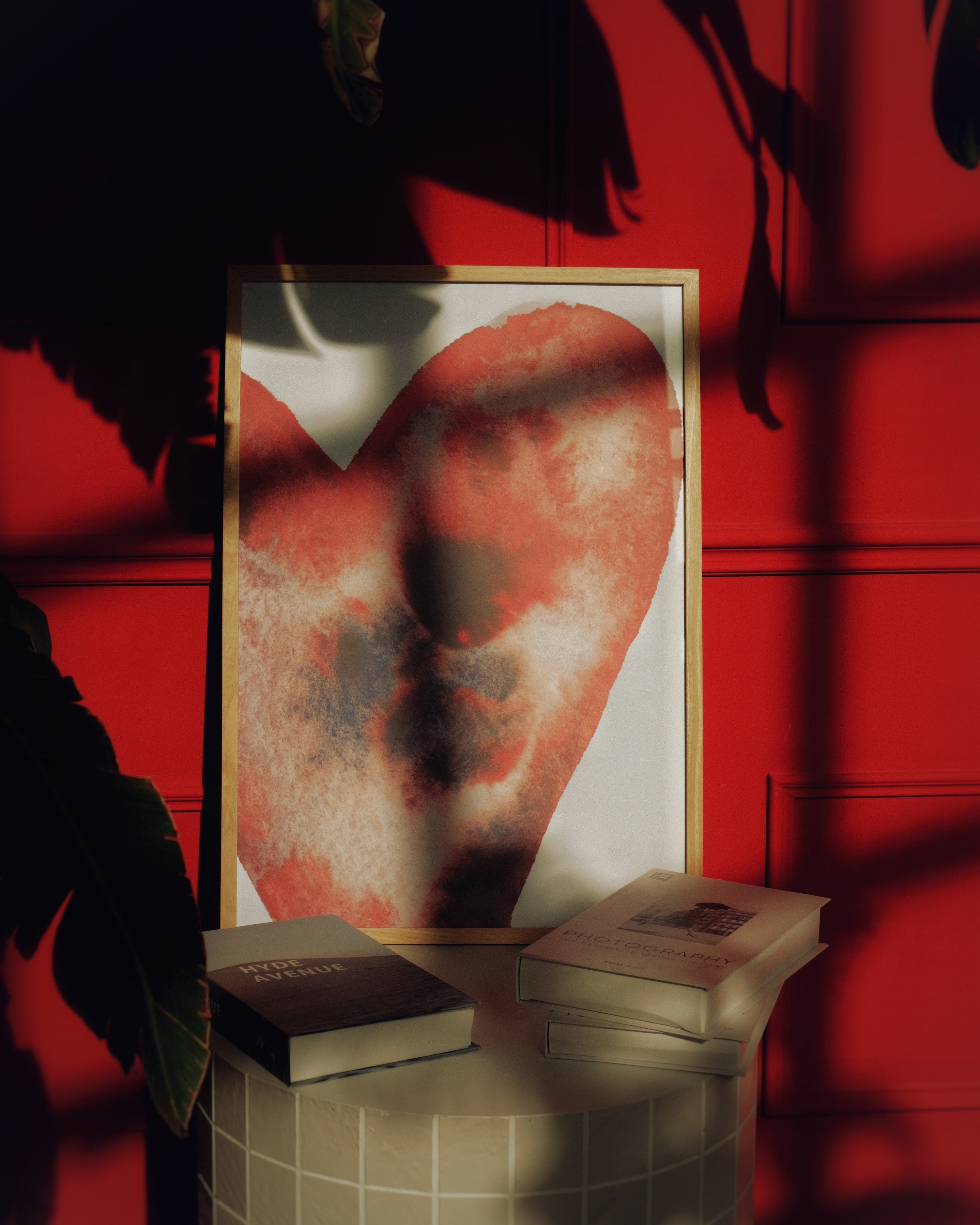 Framed artwork of a heart on a red background with books below