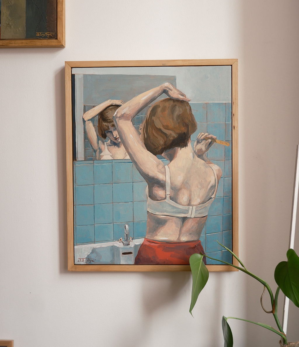 Framed artwork of a woman in a bathroom setting on a wall.