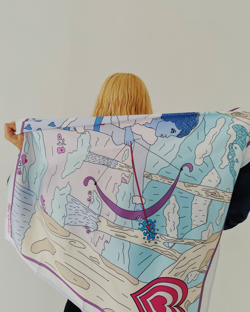 Model wearing Sagittarius zodiac art silk scarf wrapped around shoulders in soft pastel colors