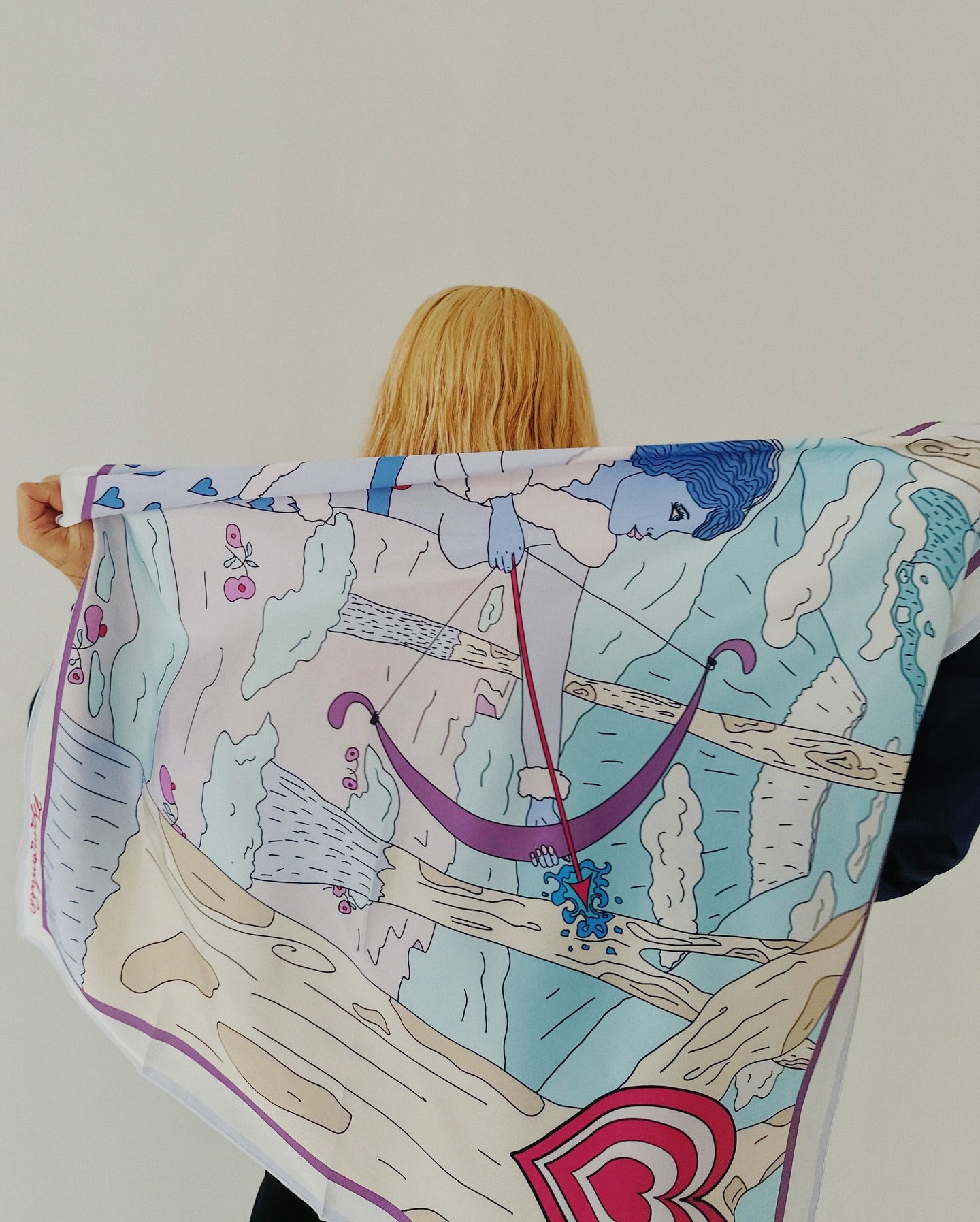 Model wearing Sagittarius zodiac art silk scarf wrapped around shoulders in soft pastel colors